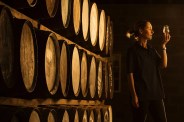 female taster looking at the colour of whisky in glass at whisky distillery