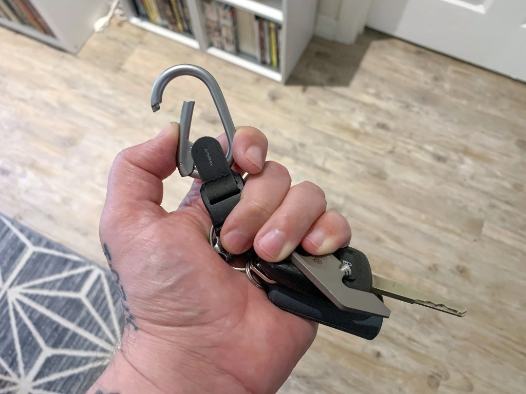someone opening the spring loaded carabiner clip on orbitkeys clip v2
