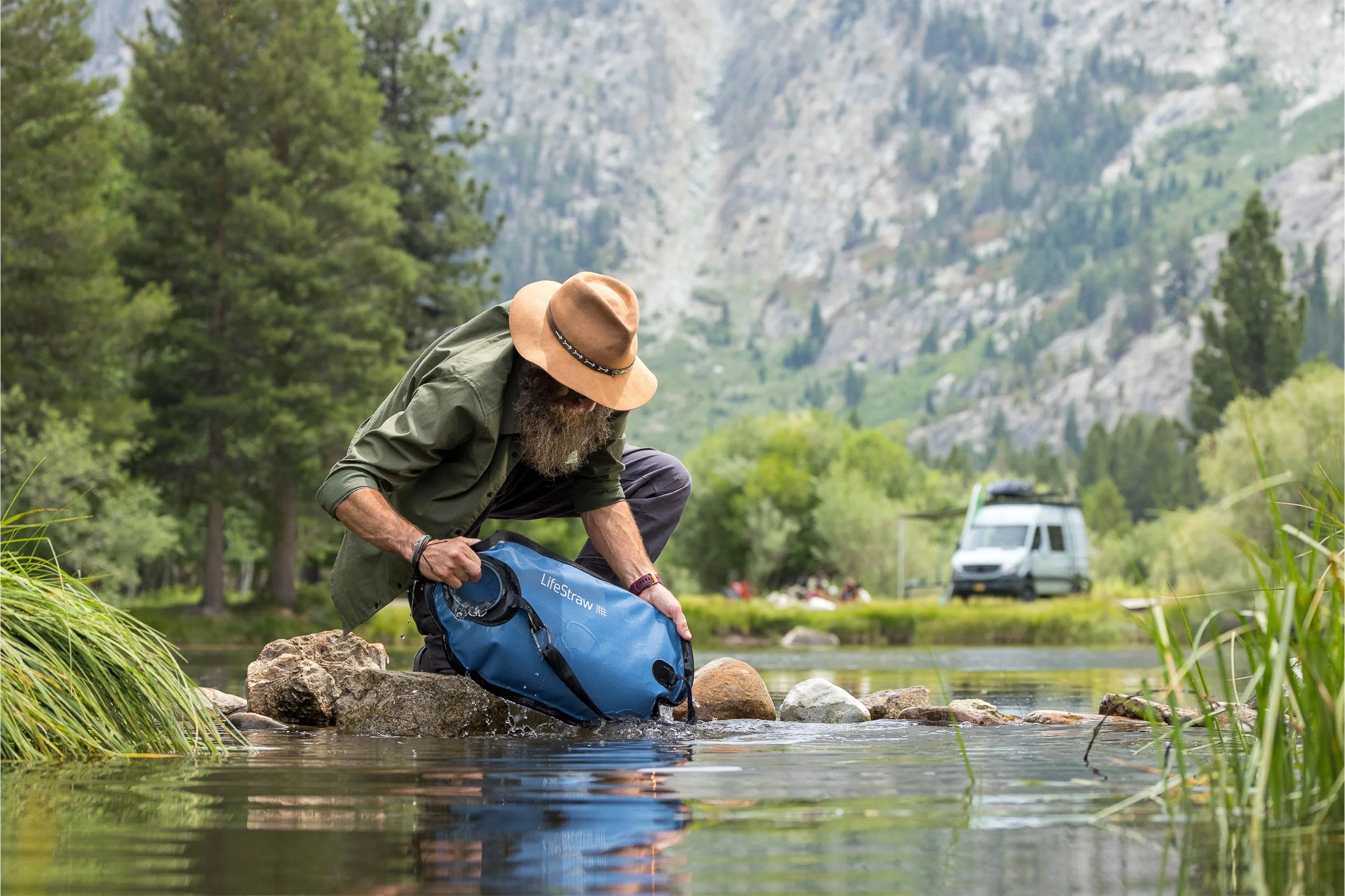 man filling up the lifestraw gravity filter in a river