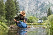 man filling up the lifestraw gravity filter in a river