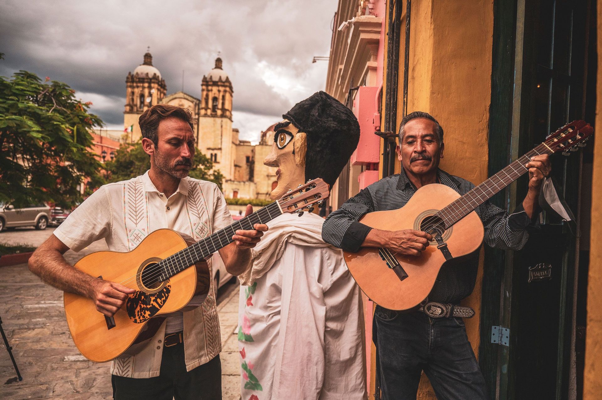 two men playing on the guitar in the streets of oaxaca