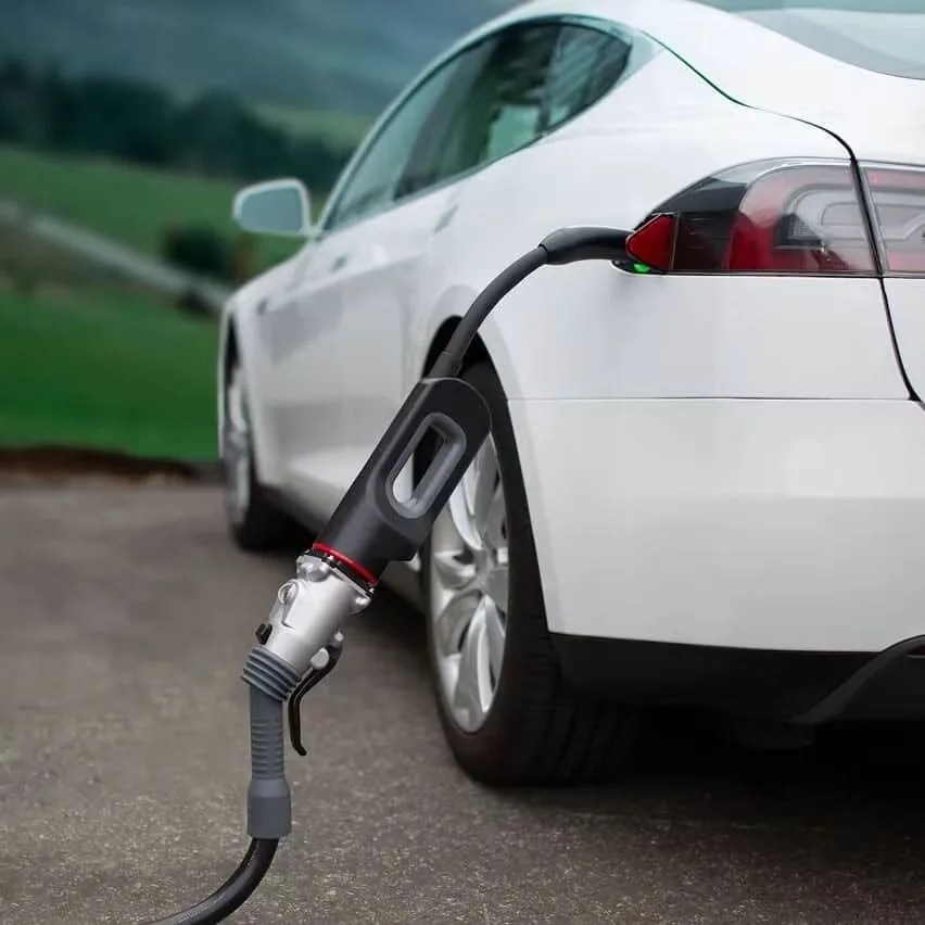 white tesla being charged with an adapter