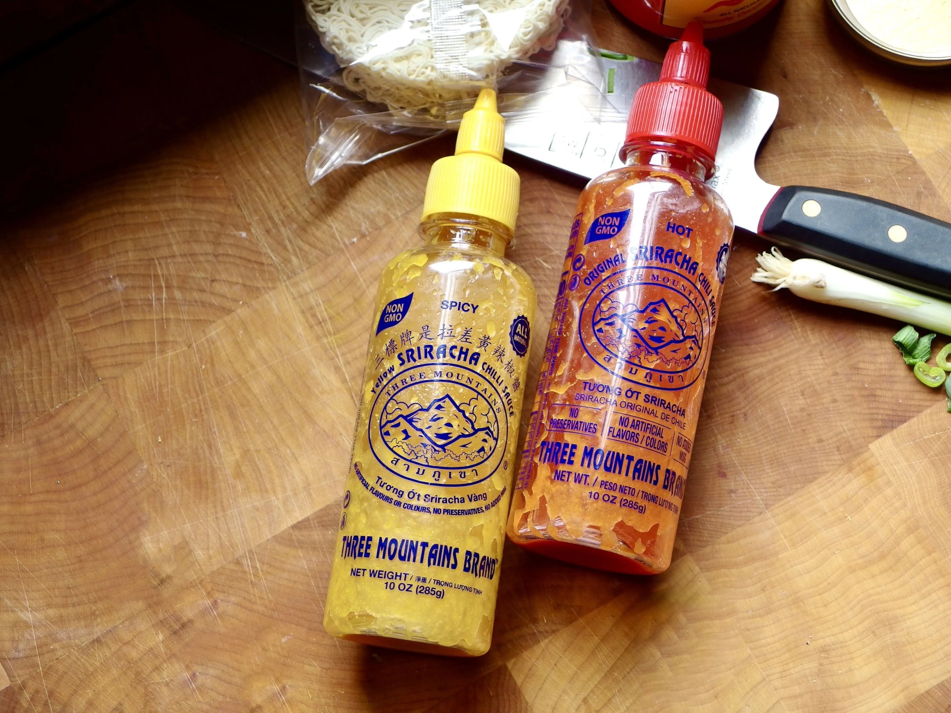 yellow sriracha on a cutting board next to red sriracha