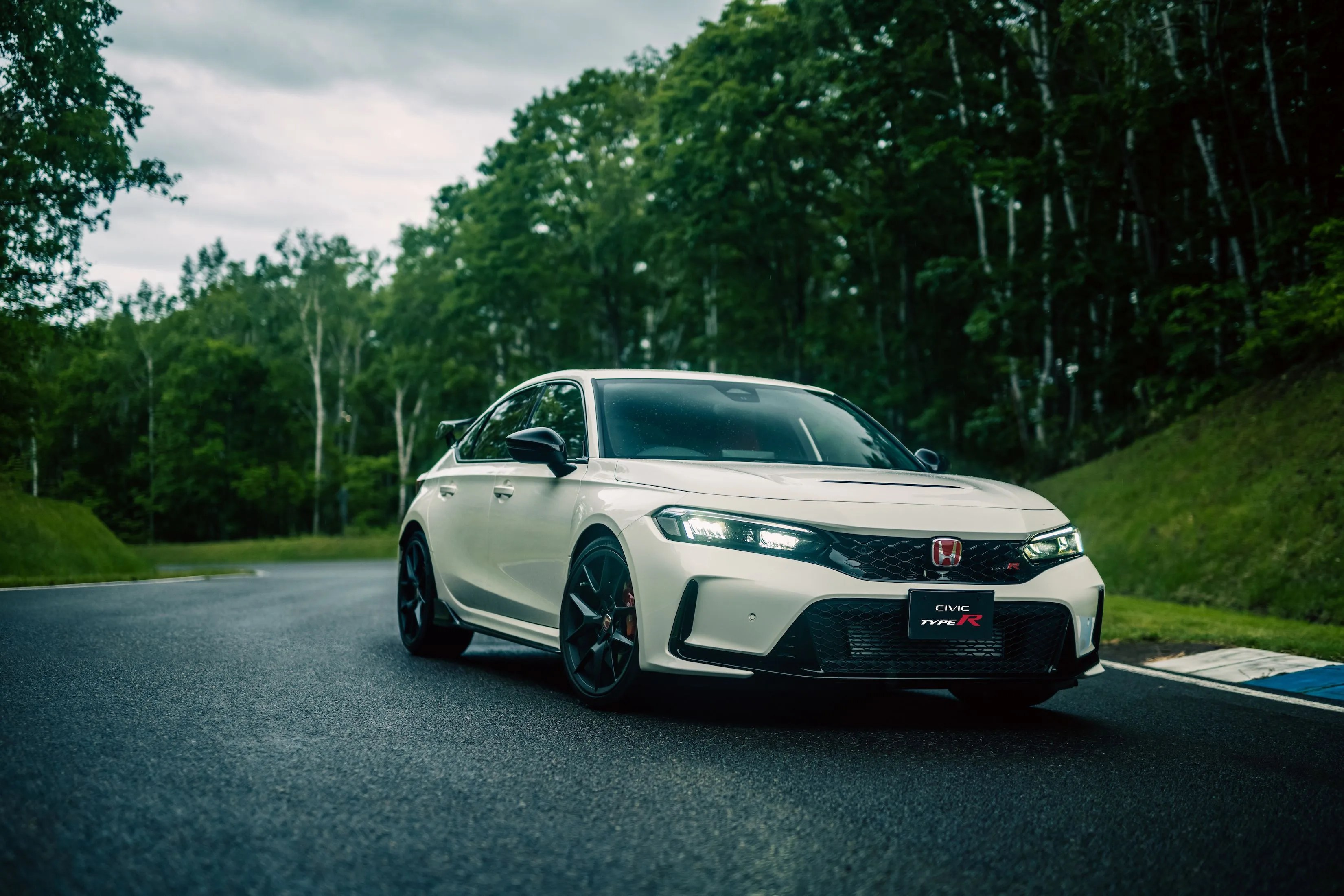 2023 honda civic type r driving on a race track with woods in the background