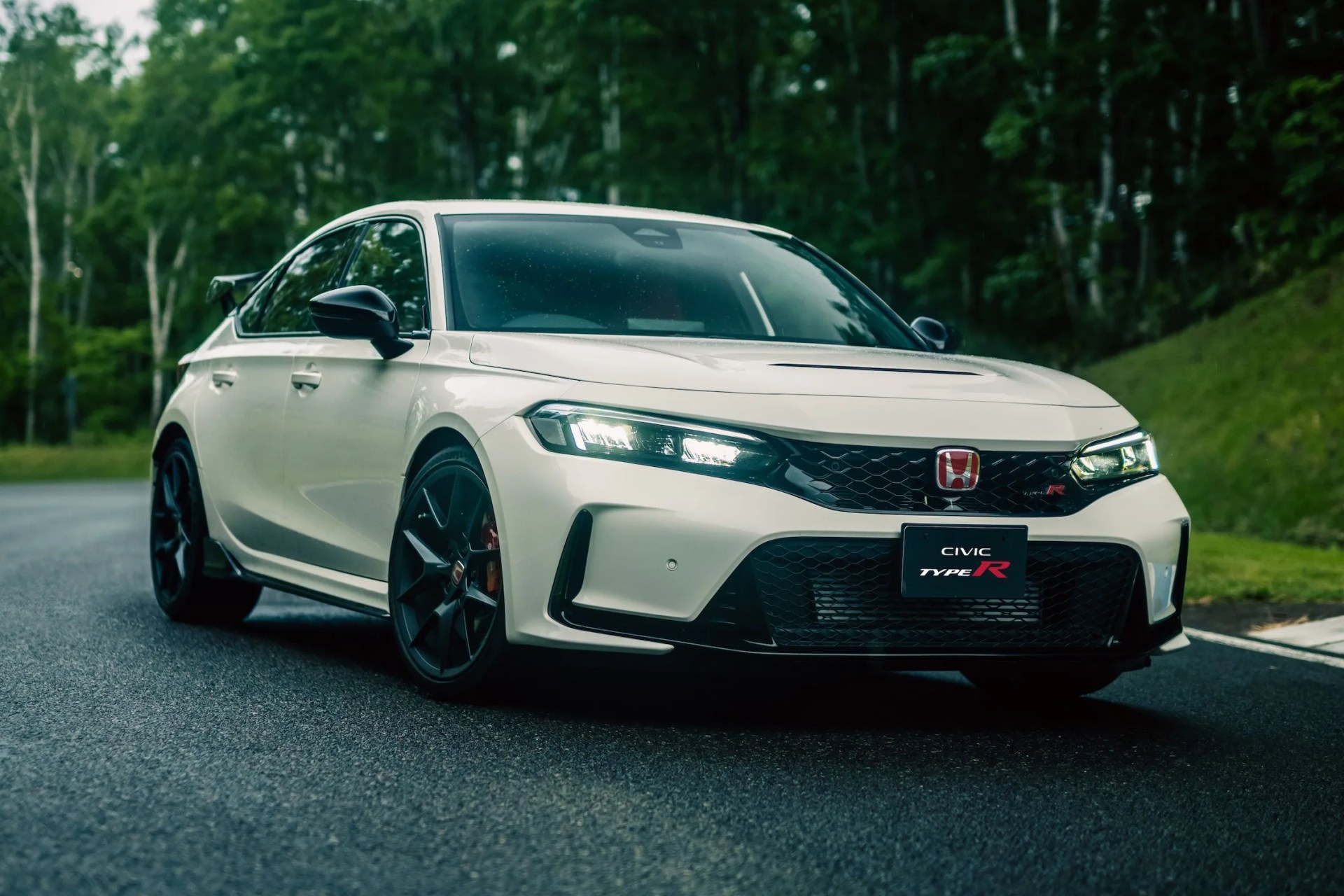2023 honda civic type r driving on a race track with woods in the background