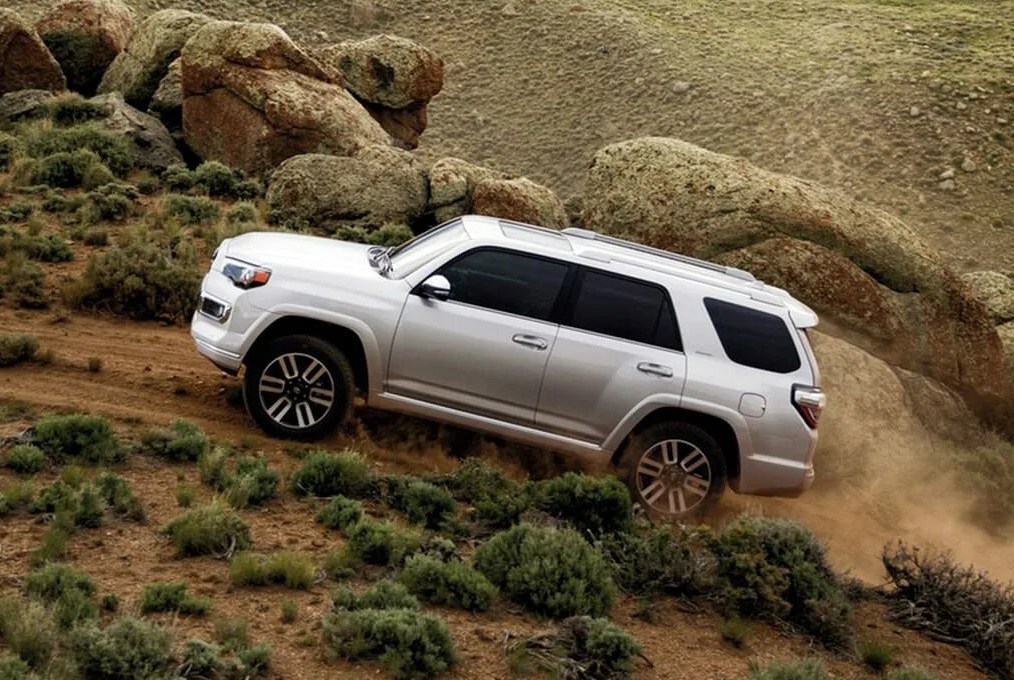 toyota 4runner from the side driving up hill on a desert mountain