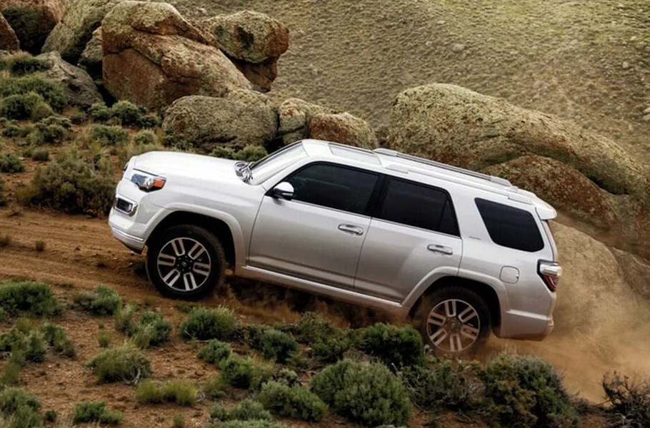 toyota 4runner from the side driving up hill on a desert mountain