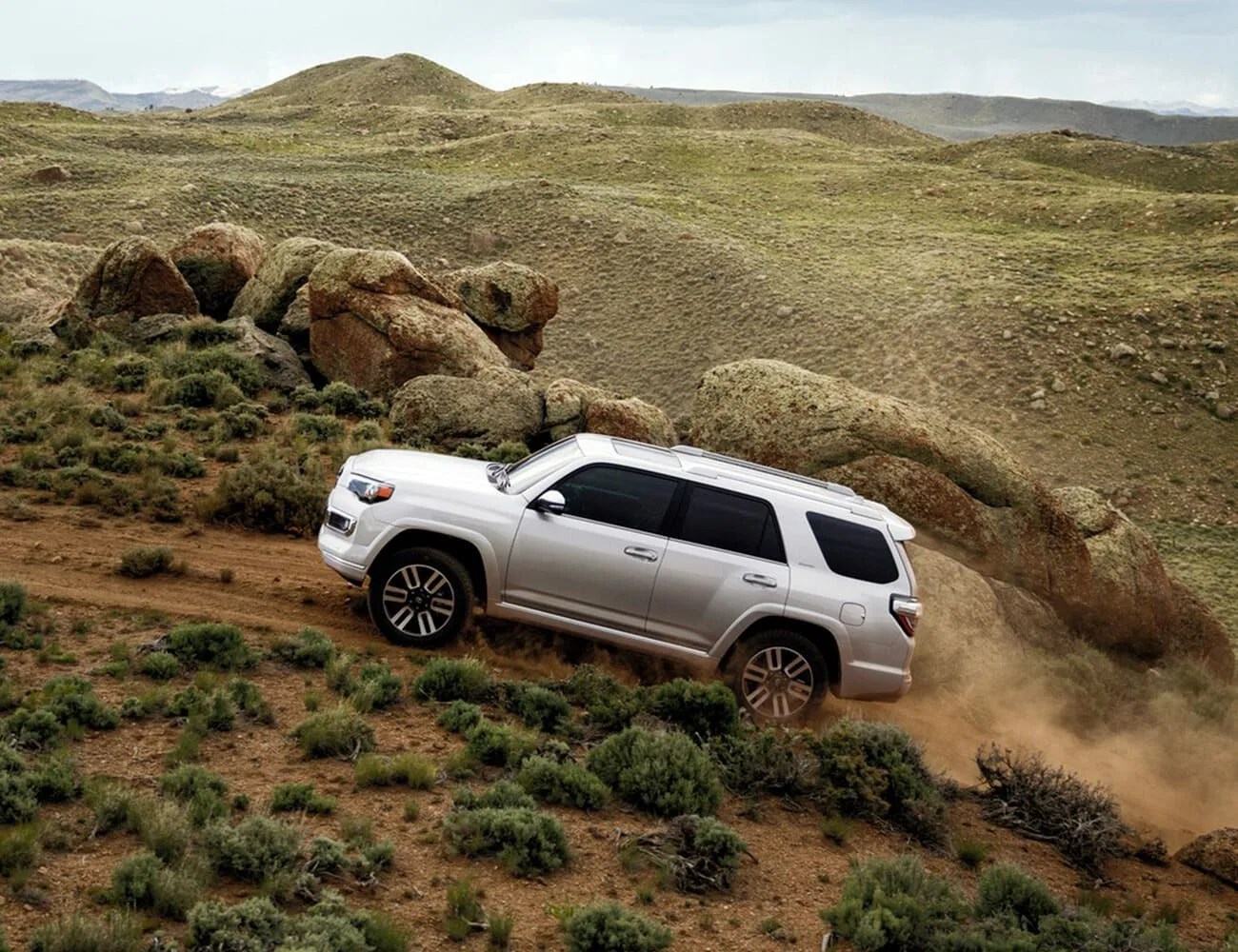 toyota 4runner from the side driving up hill on a desert mountain