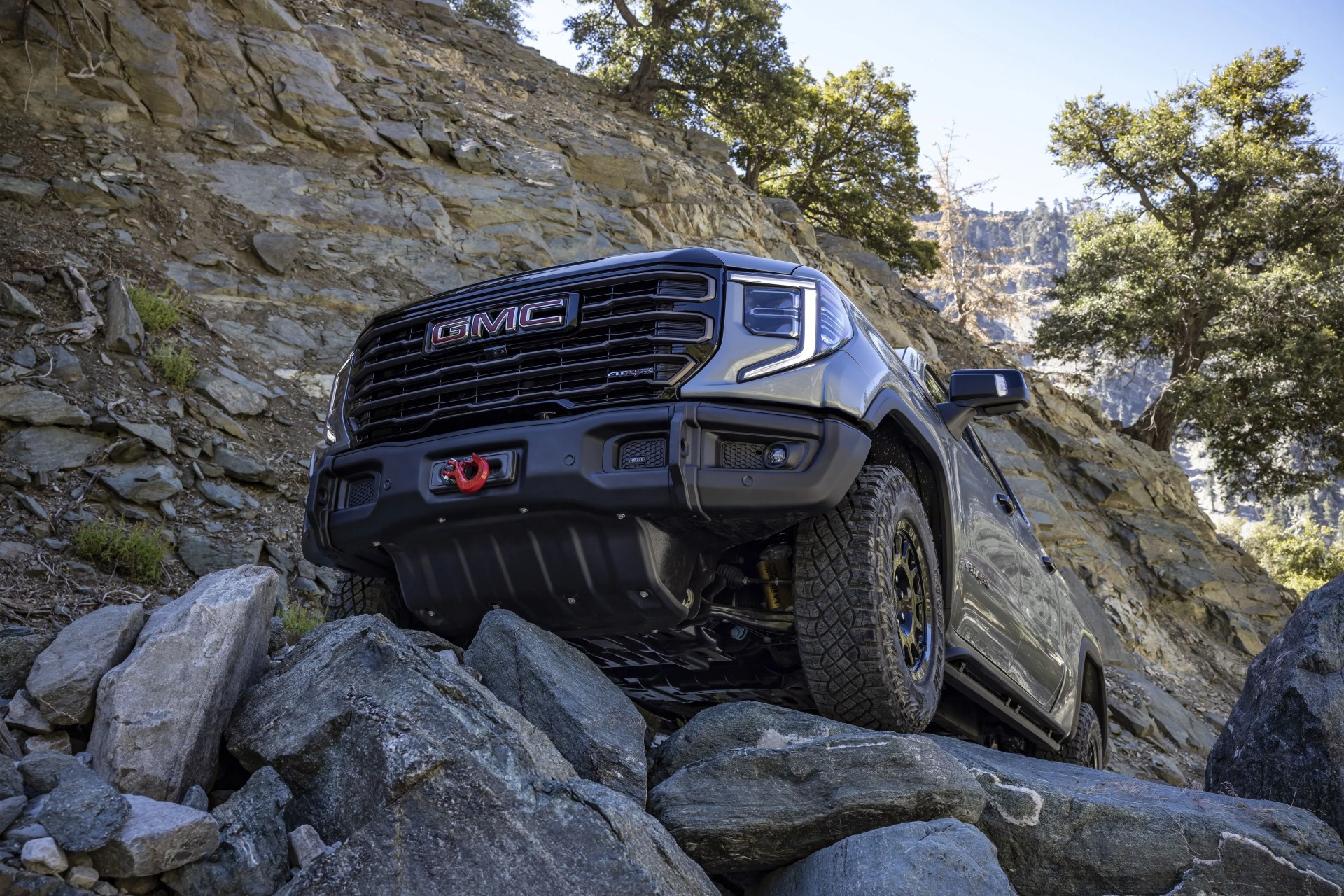 the 2023 gmc sierra 1500 at4x aev edition maneuvering over off road rocks the aev edition includes a winch capable front bumper and five boron steel underbody skid plates
