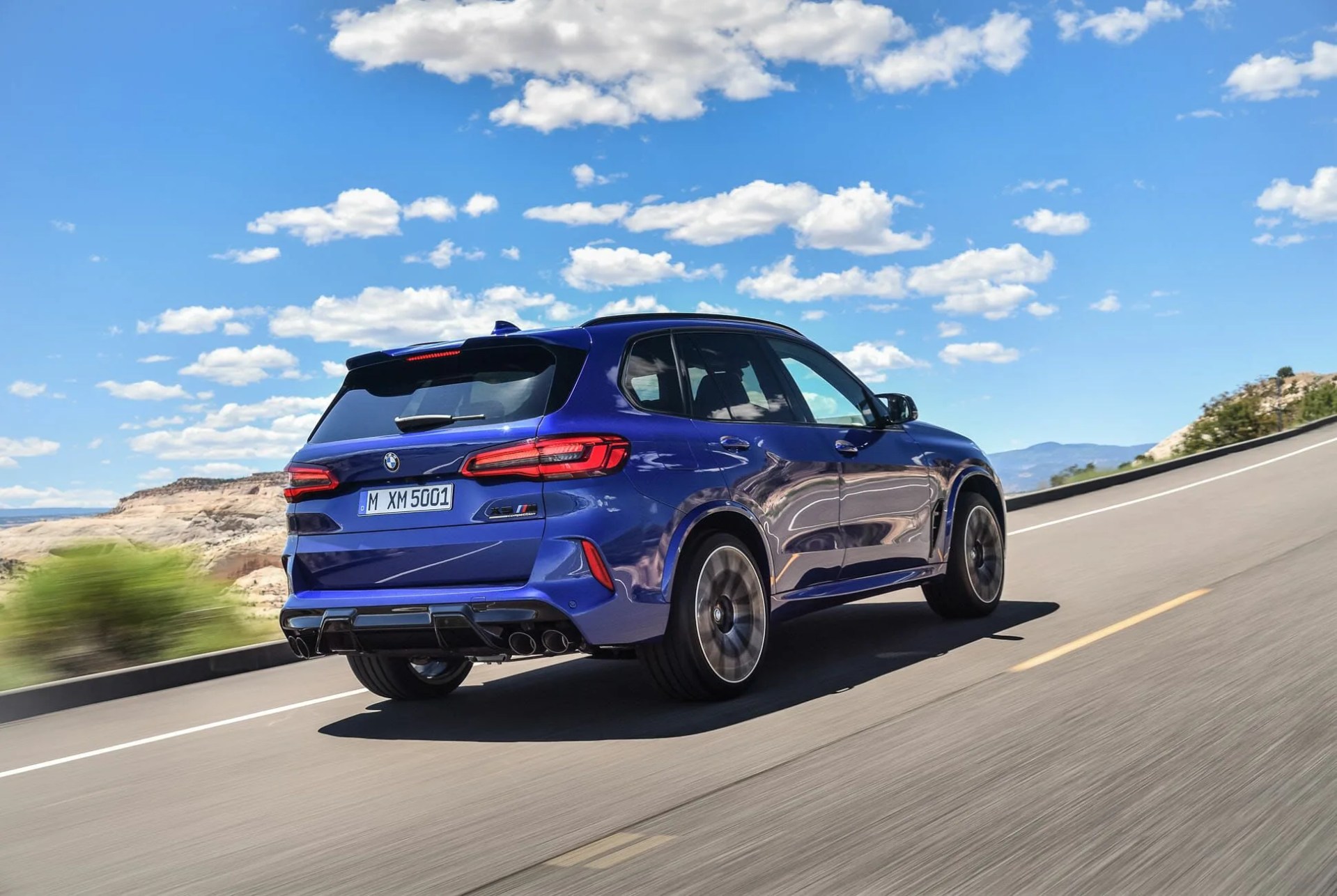 bmw x5m driving on a road in the desert