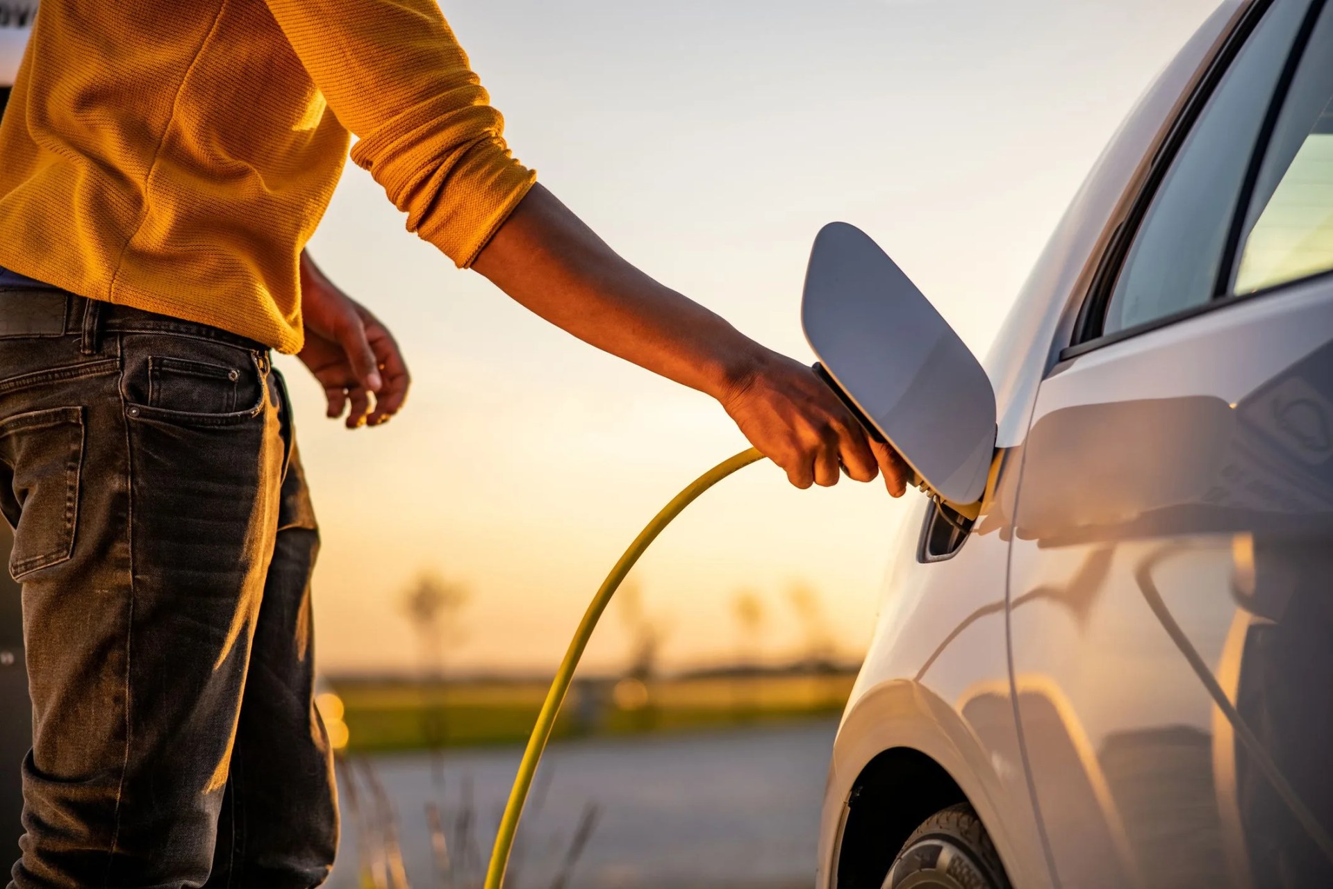 african american man inserting plug into the electric car charging socket