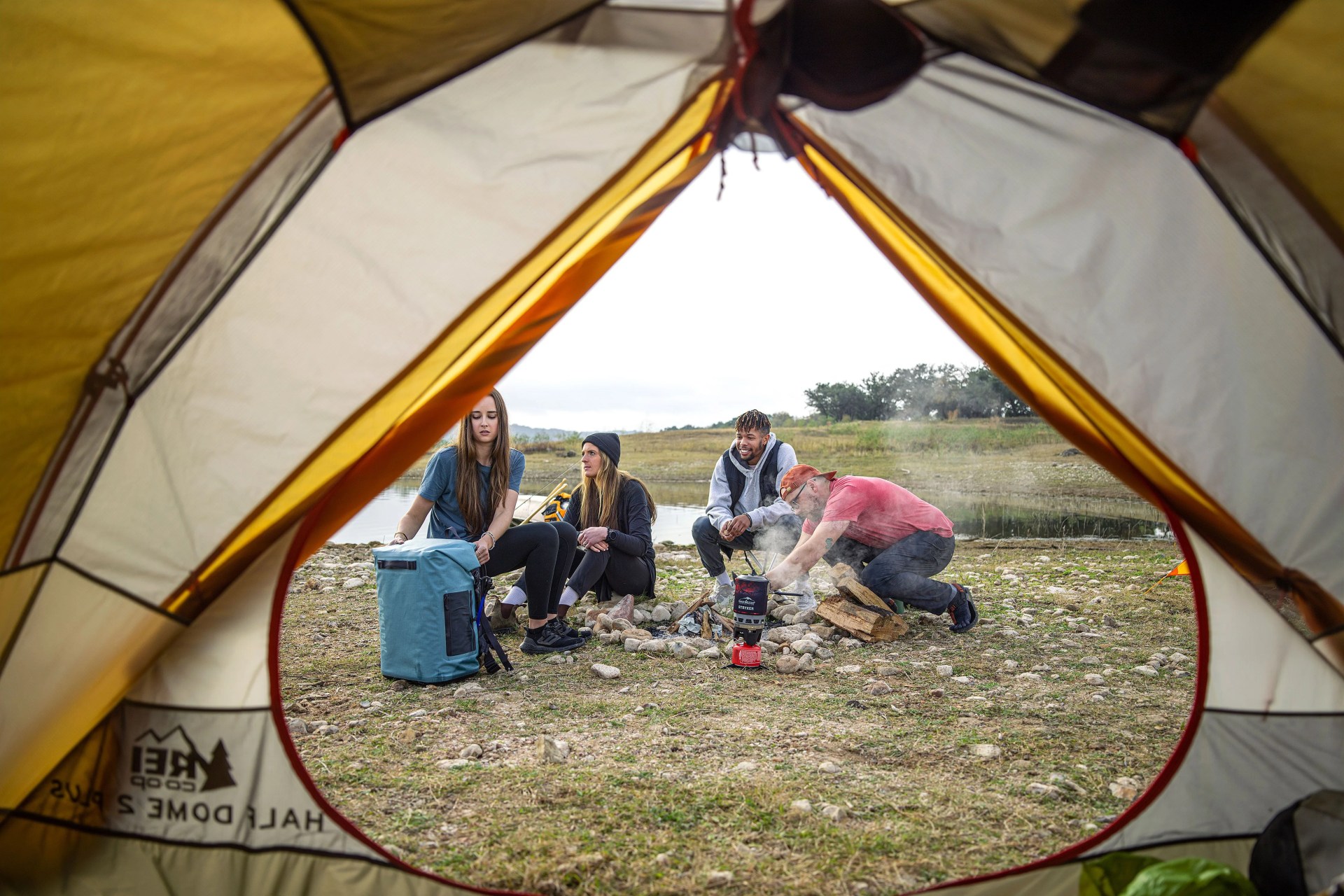 a group of friends camping around a fire with camelbak chillbak pack 30