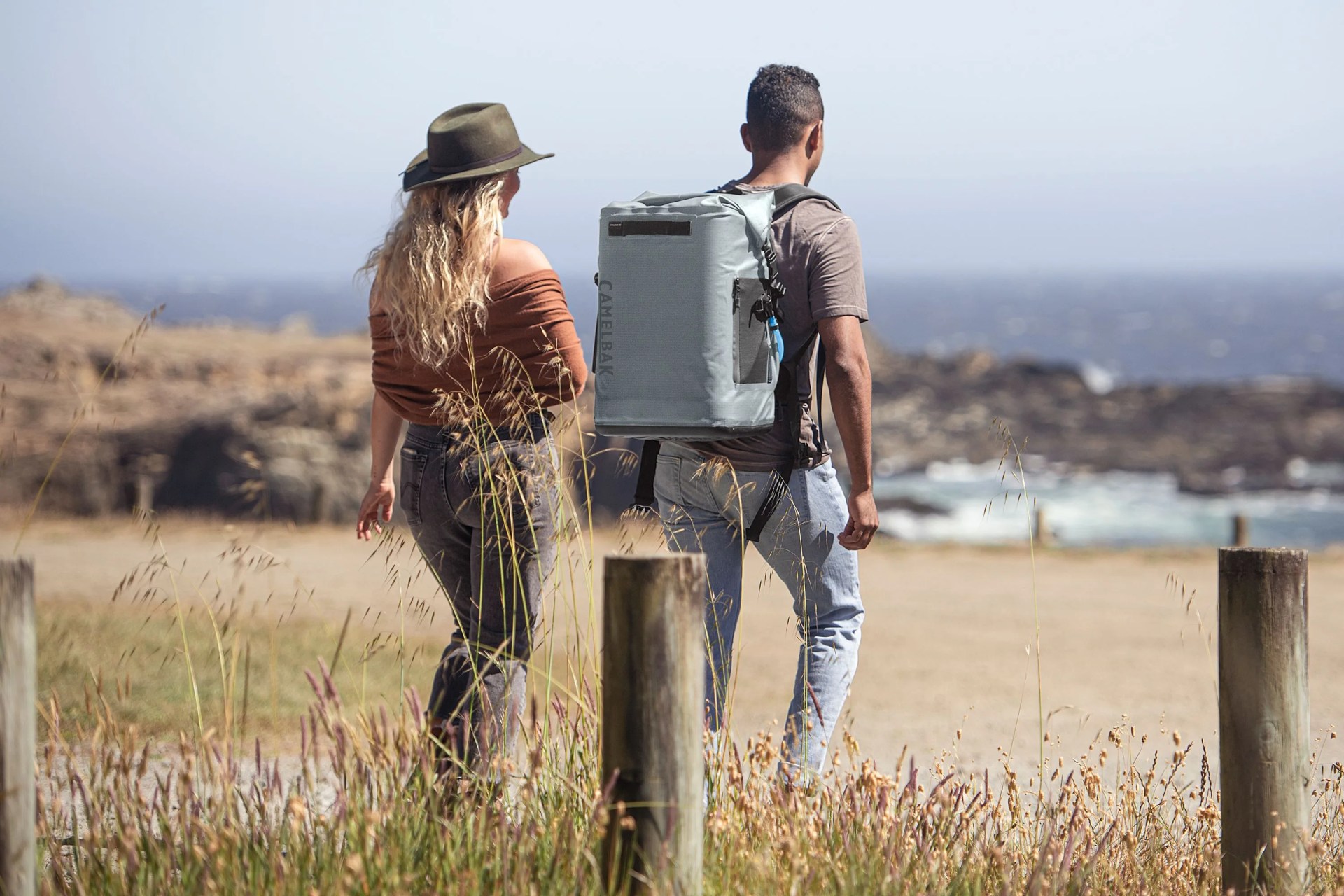 two people walking to the coast line, one wearing the camelbak chillbak backpack cooler