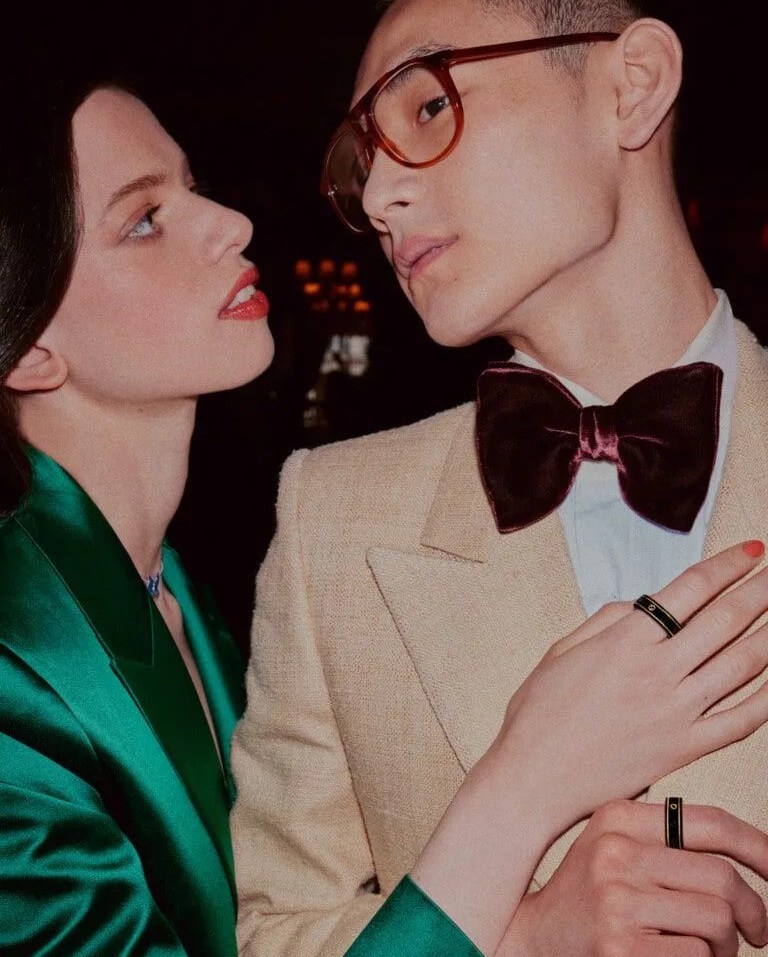 woman looking at man with hand placed on his chest both are wearing gucci x oura ring