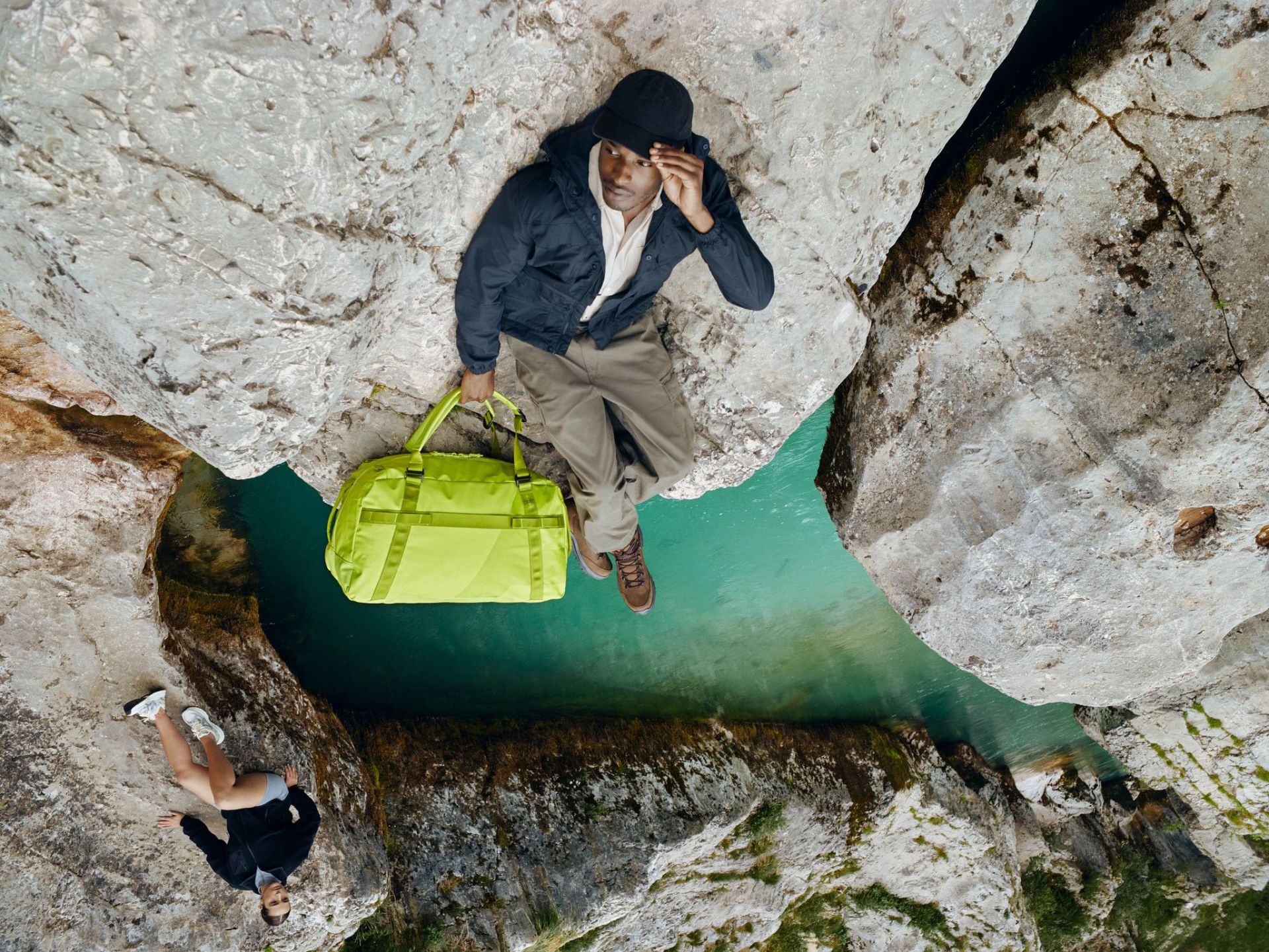 man holding away duffle sitting on a side of a cliff