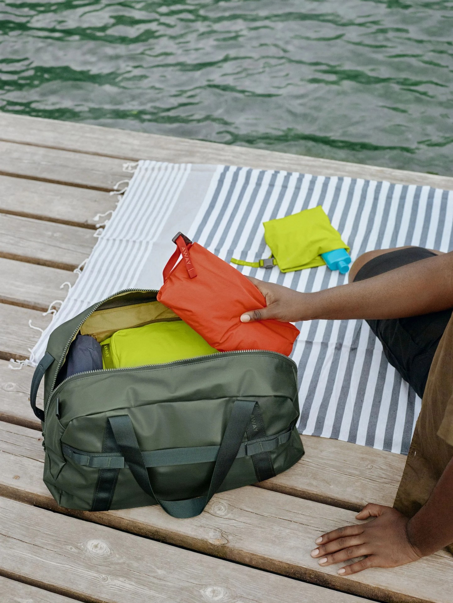 someone sitting on a dock packing an away duffel