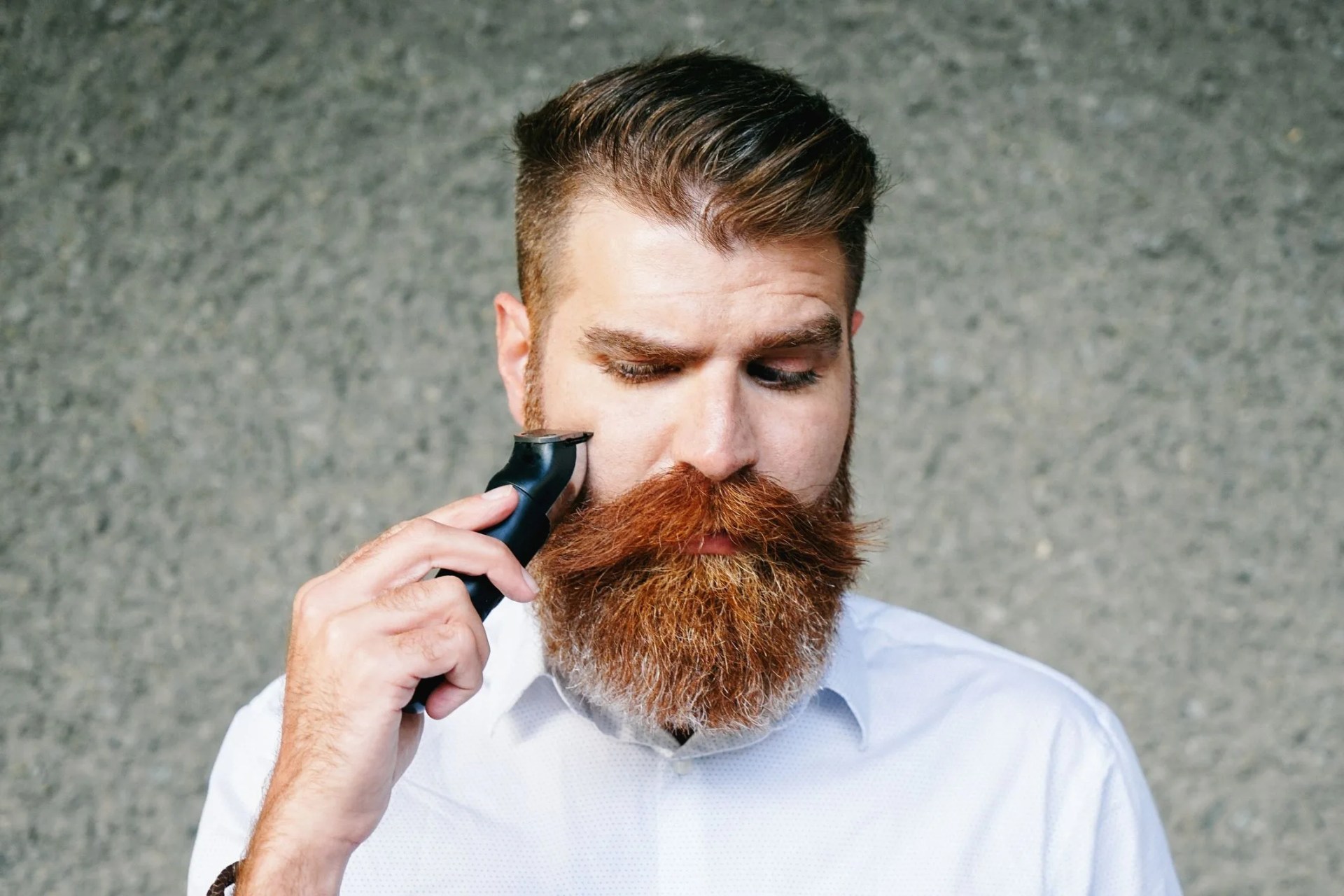 portrait of bearded man trimming his beard