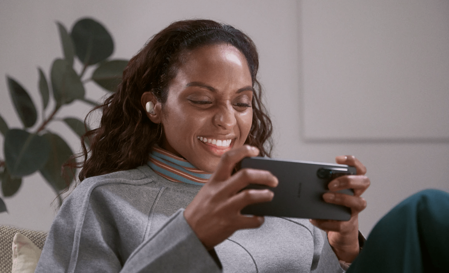 smiling woman wearing sony linkbuds s and playing on her phone