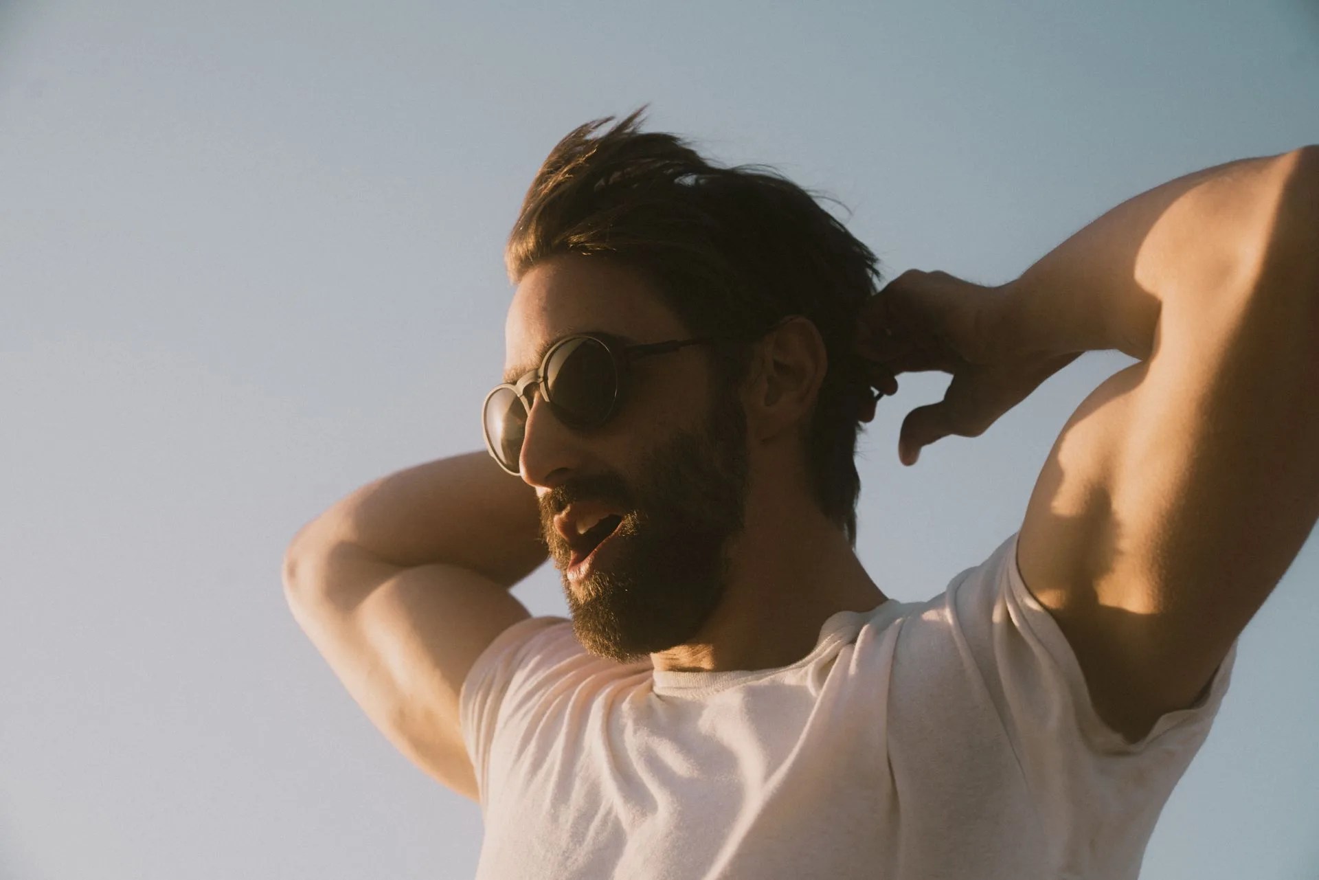 man with arms behind head wearing ombraz sunglasses