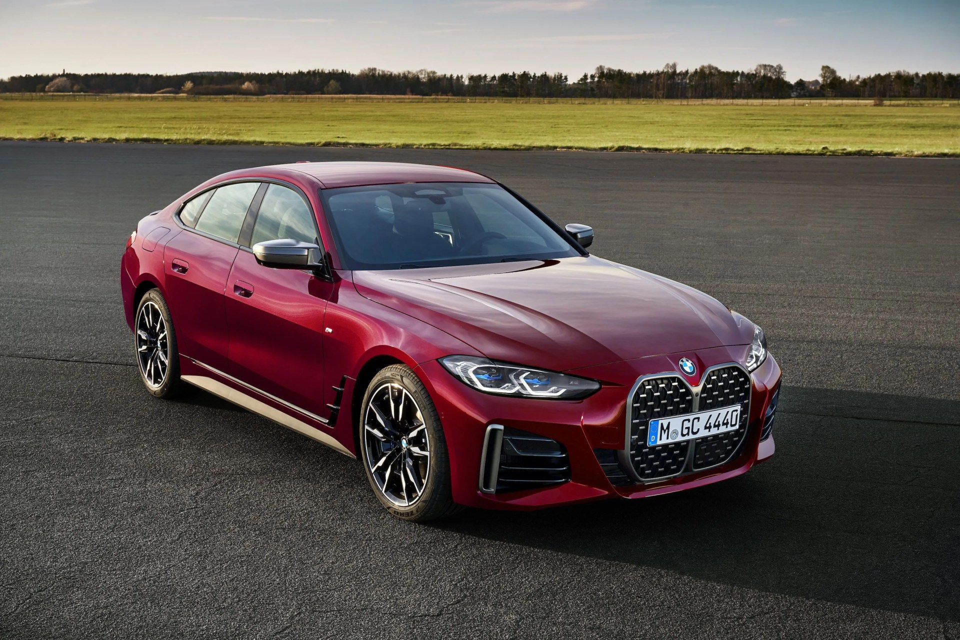 bmw 4 series parked on a track with a field and forest in the background