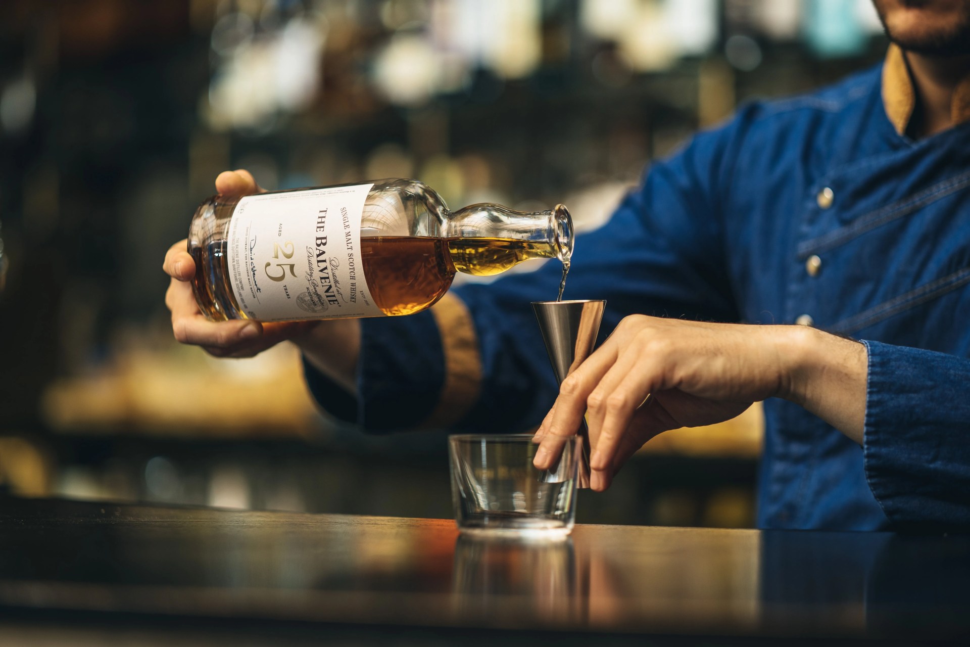 someone pouring the balvenie twenty five scotch whiskey