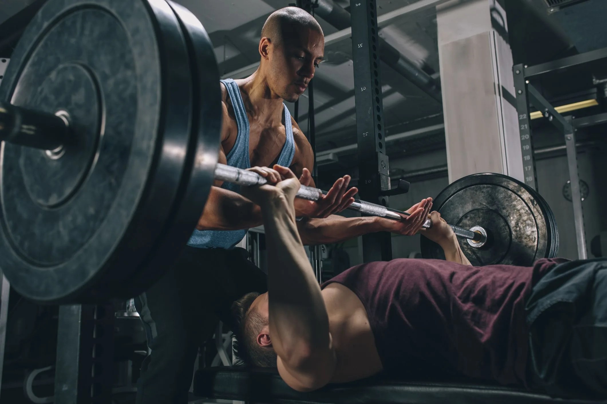 two friends exercising bench press in gym