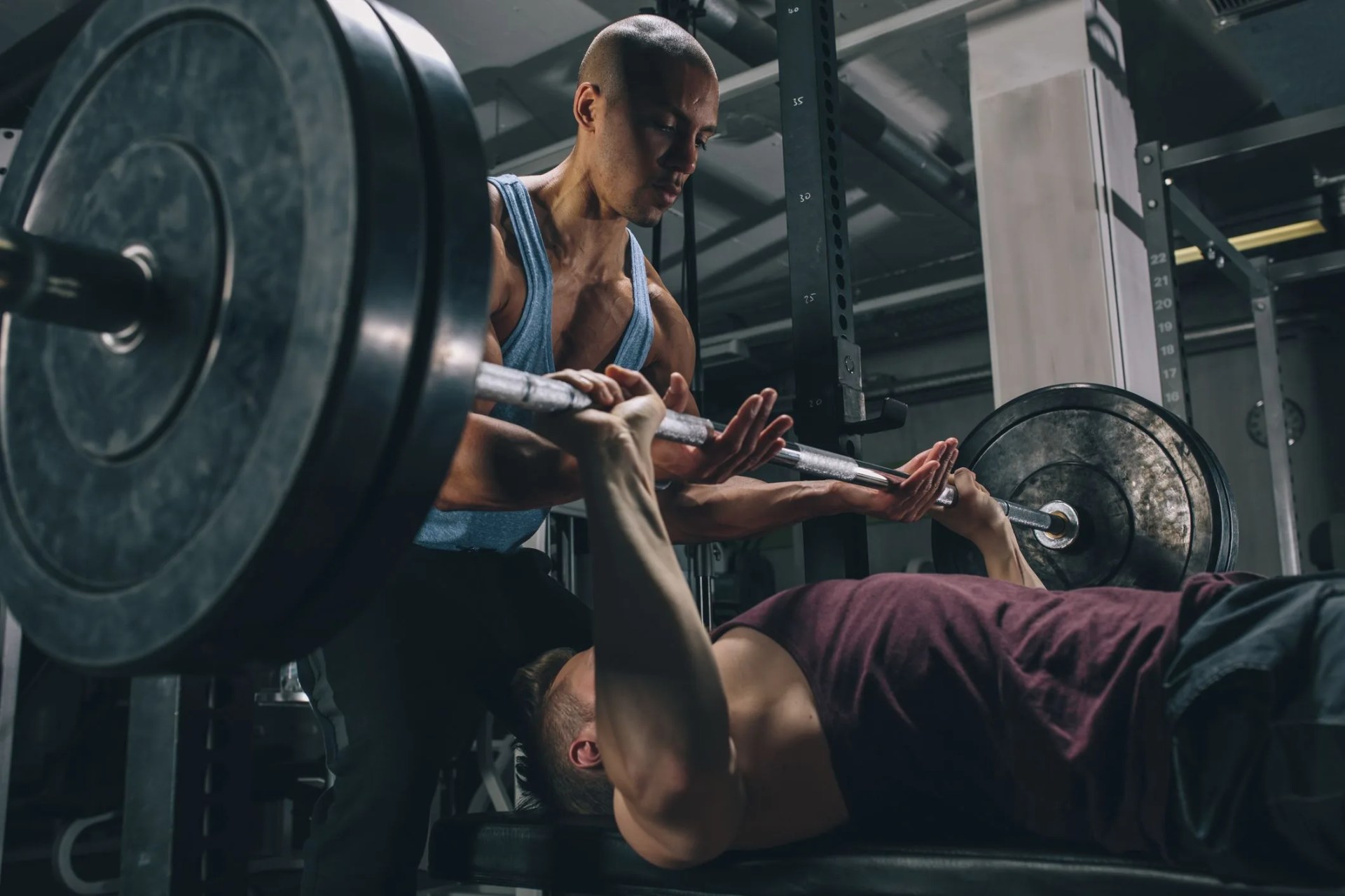 two friends exercising bench press in gym