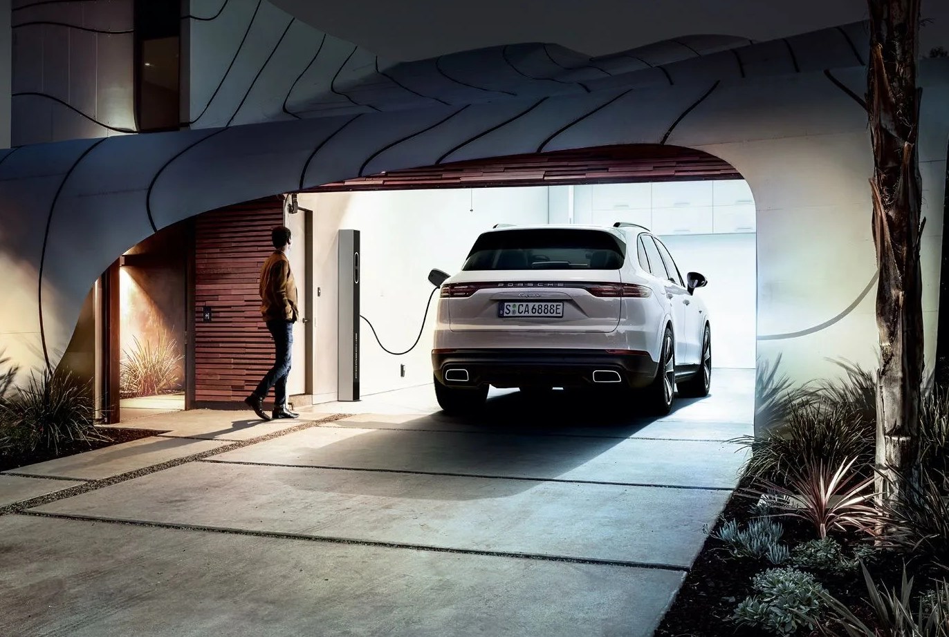 porsche cayenne e hybrid plugged into wall outlet in a garage