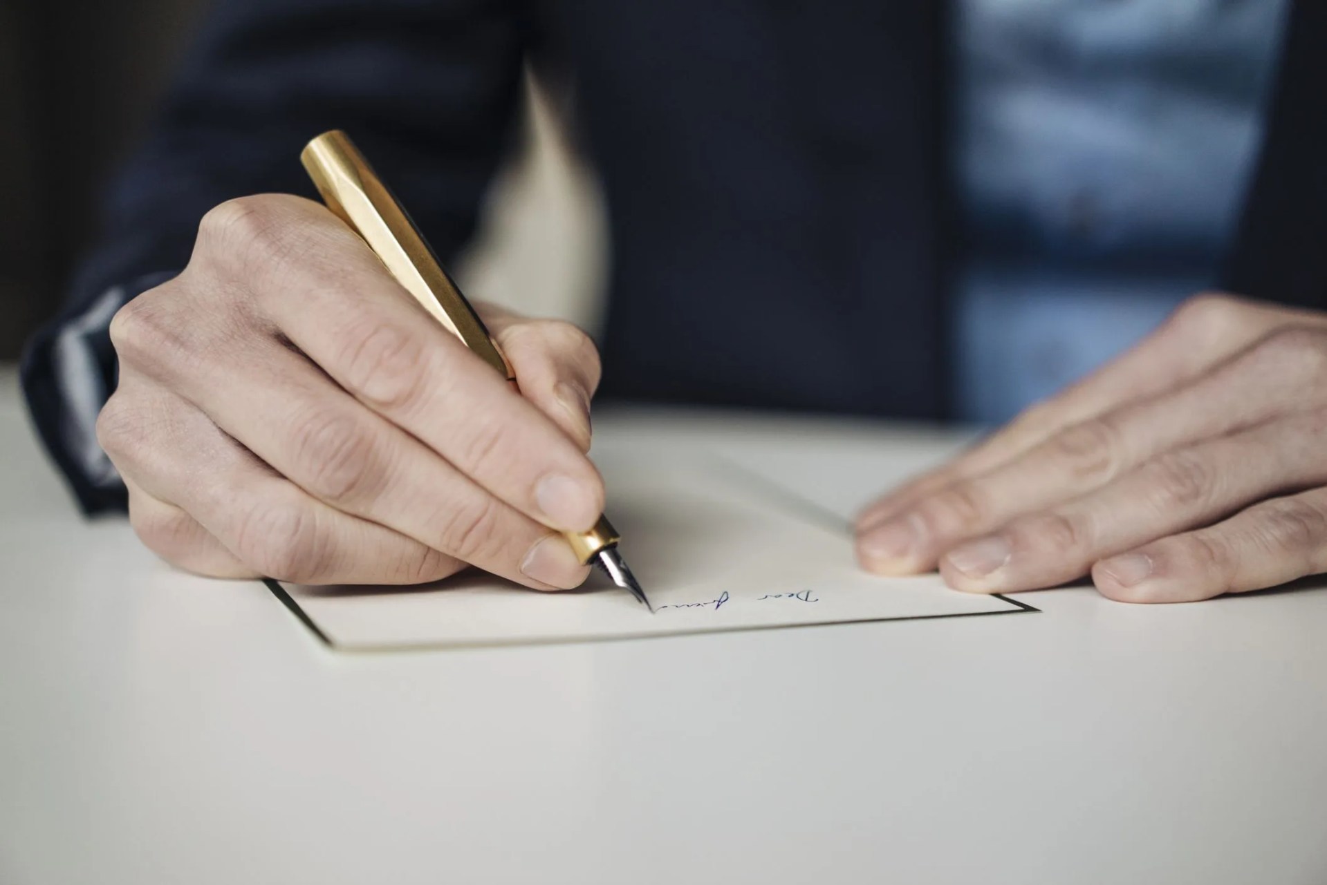 hand of businessman writing with golden fountain pen