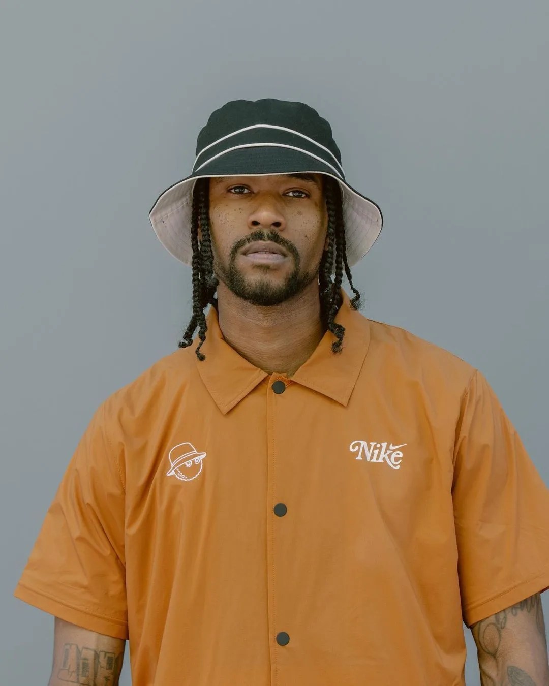 man wearing a bucket hat and orange button down shirt