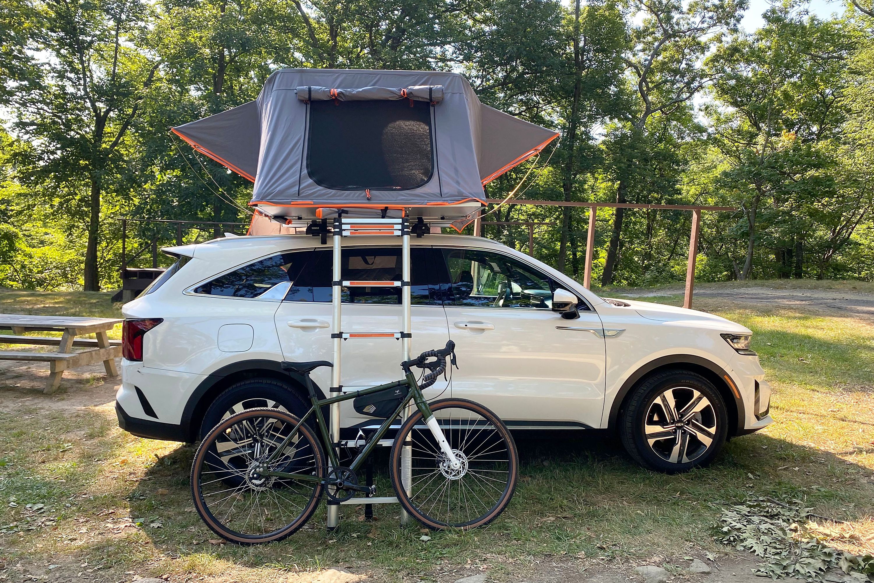 roofnest condor xl tent on top of a white kia with a ladder and bike in front
