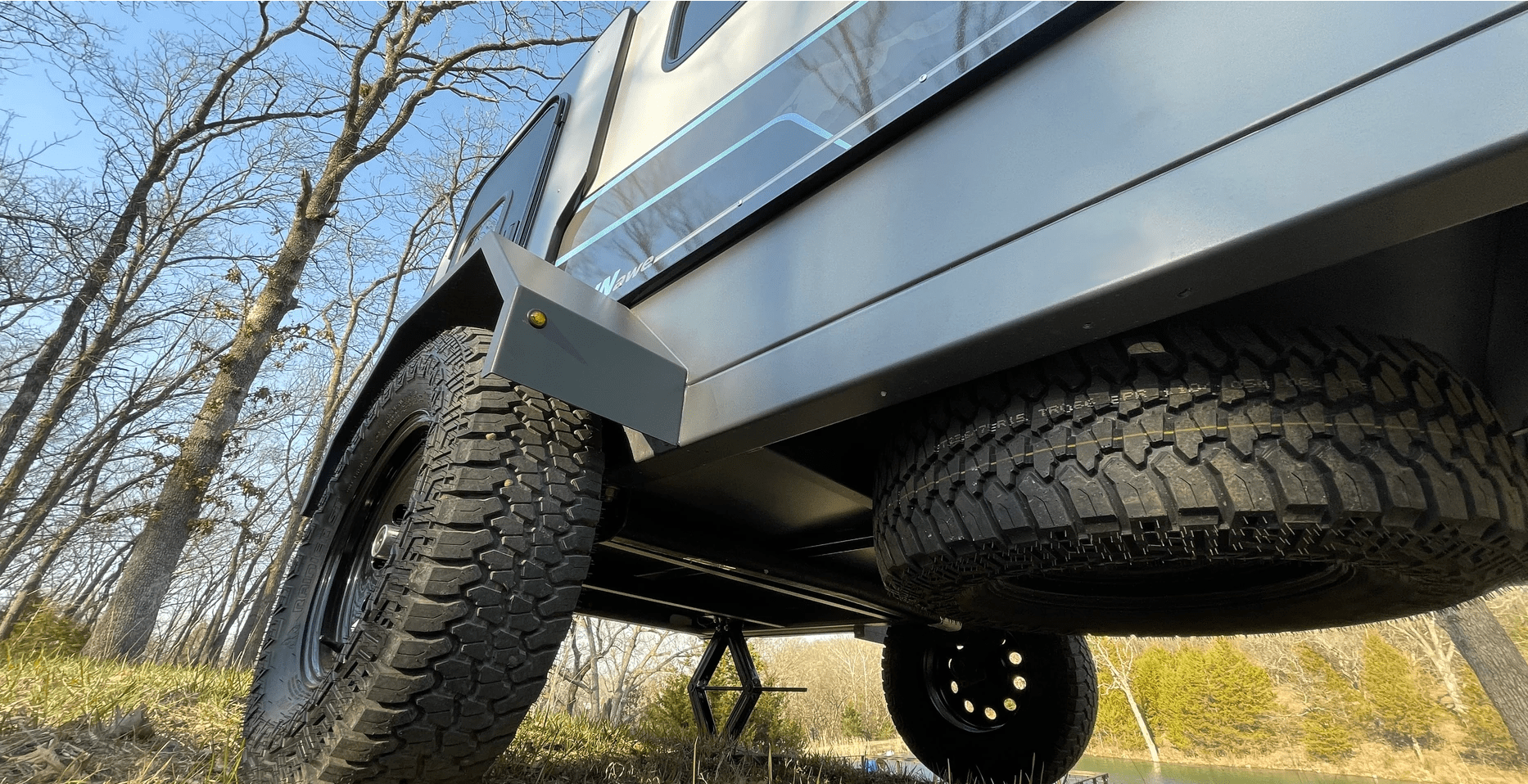 underneath campinawe camping trailer with all terrain tires and a spare