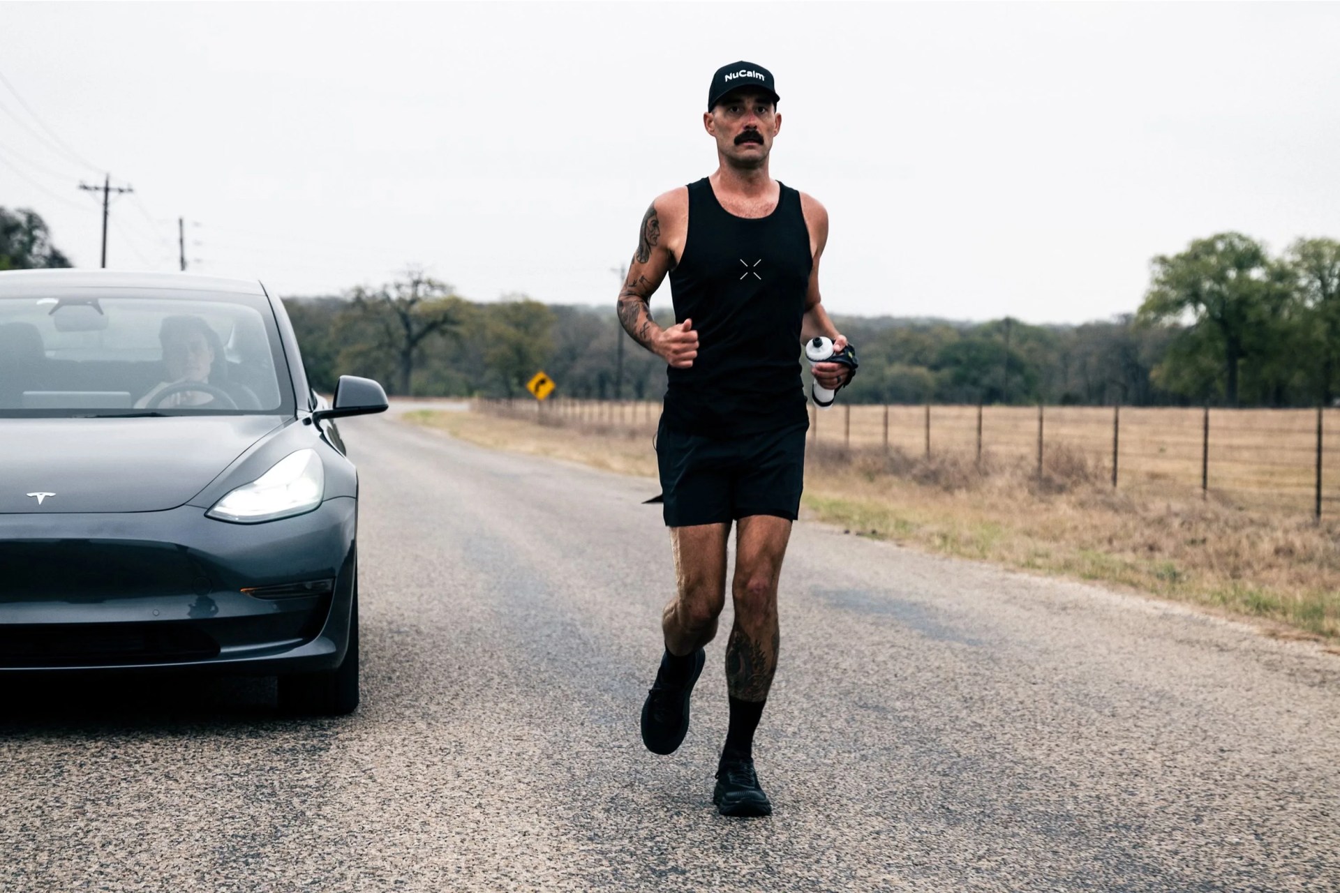 runner racing next to tesla