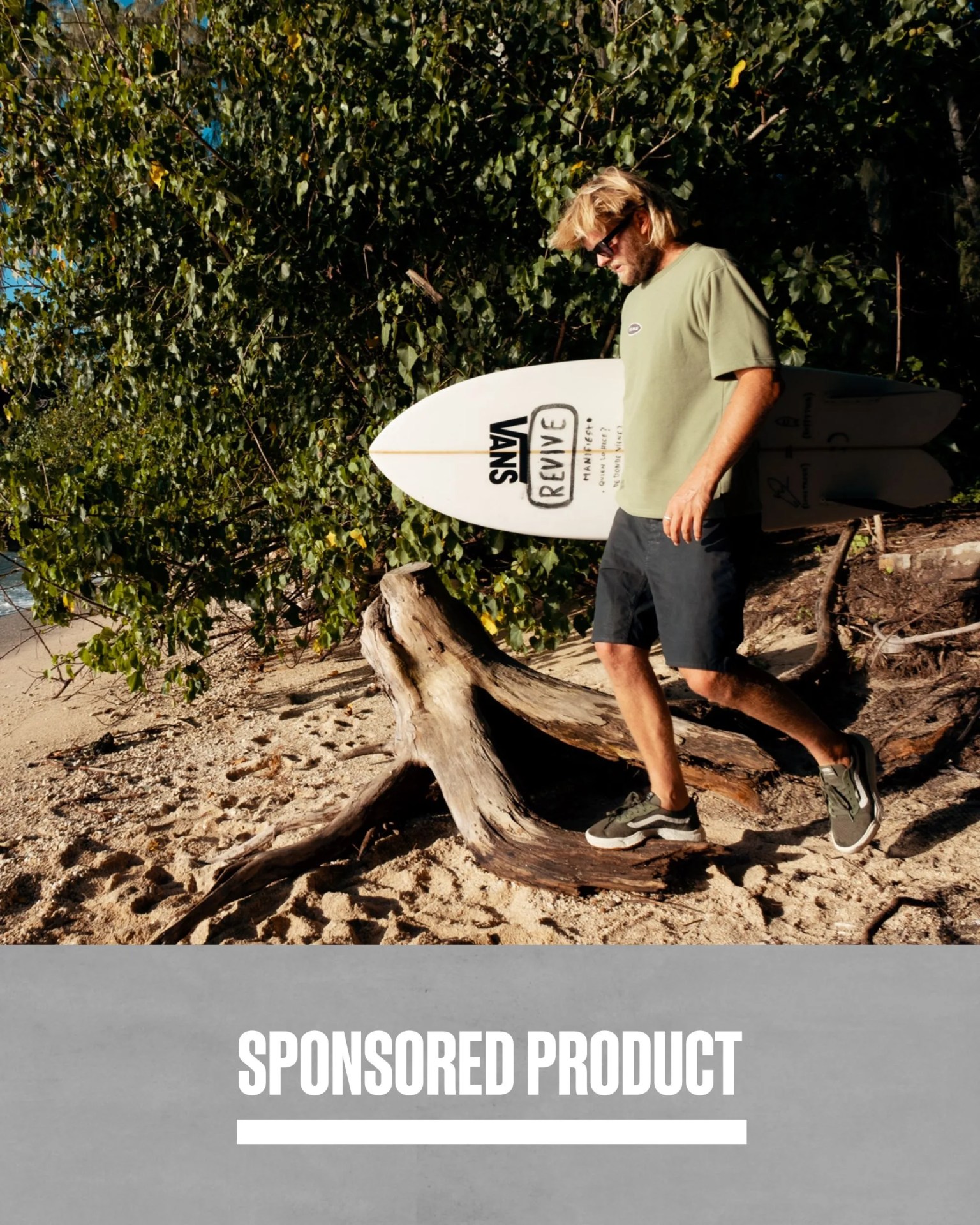 sponsored product man carrying surfboard walking along beach wearing vans sneakers