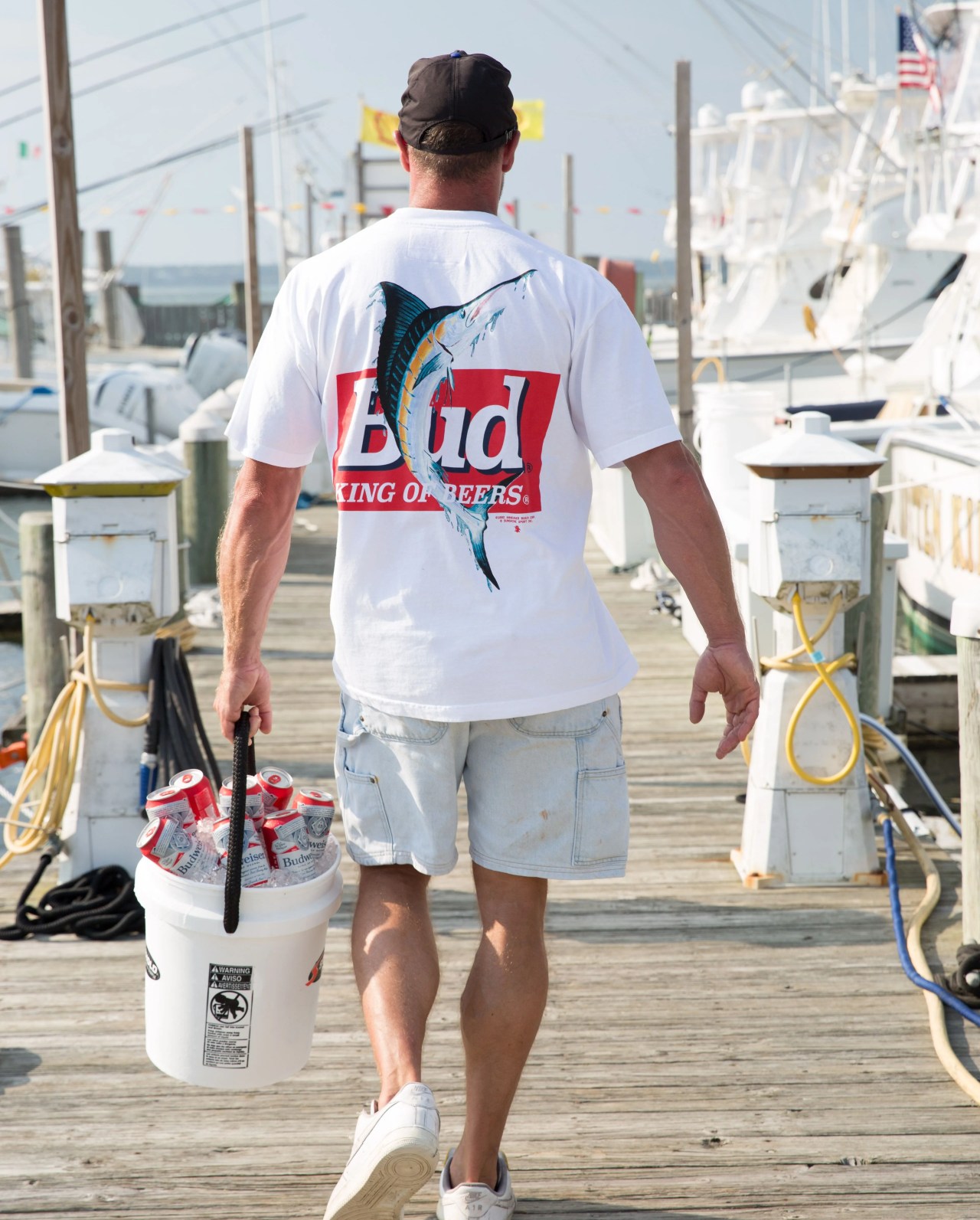 man walking down pier carrying beer wearing the new york sunshine budweiser collection