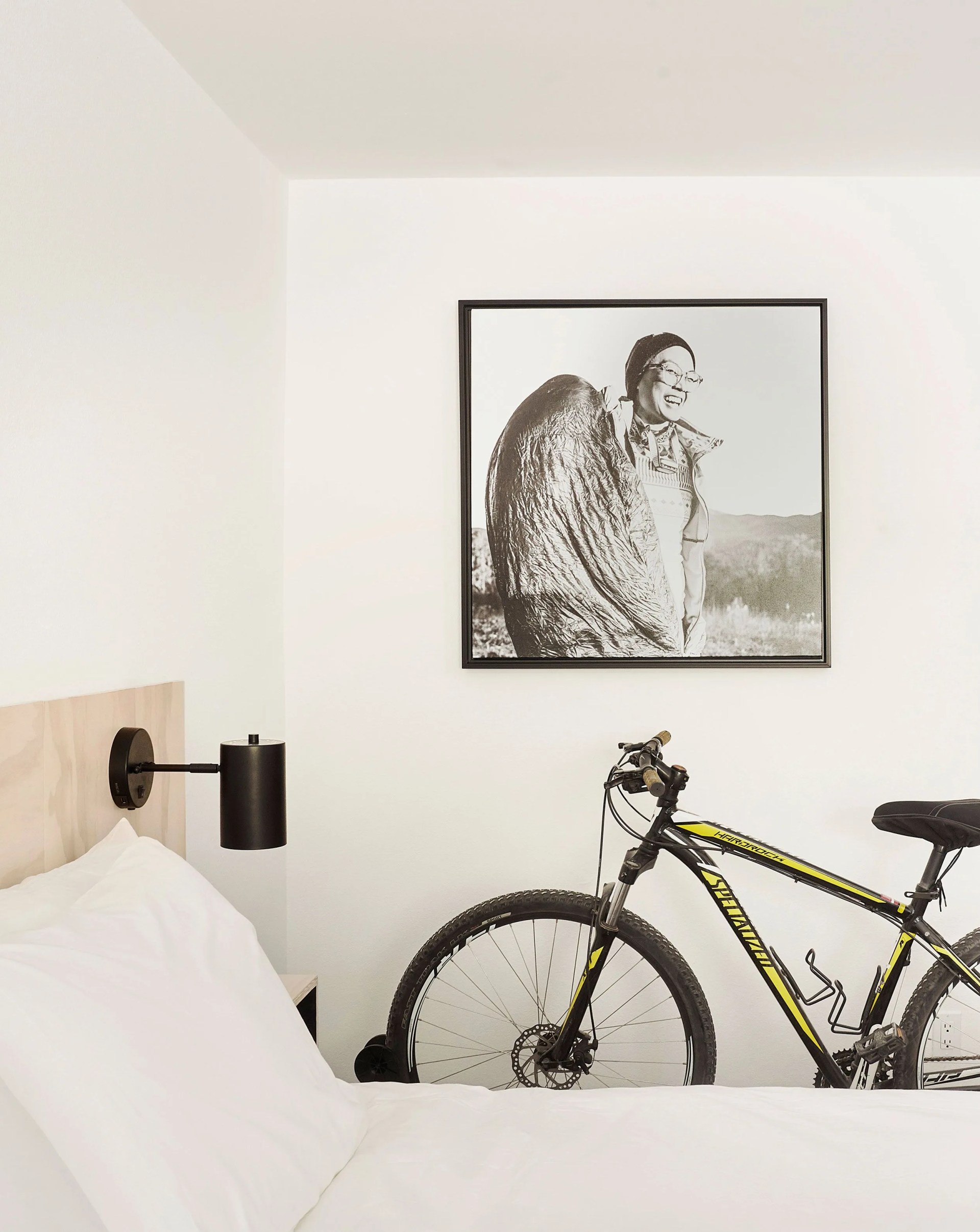 field station hotel room with a bed, painting, and bike