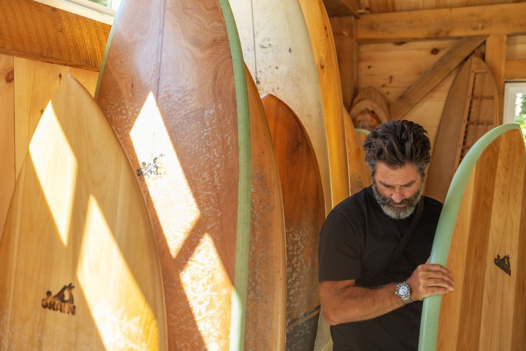 nick lavecchia wearing seiko watch selecting a surfboard from a group of wooden boards