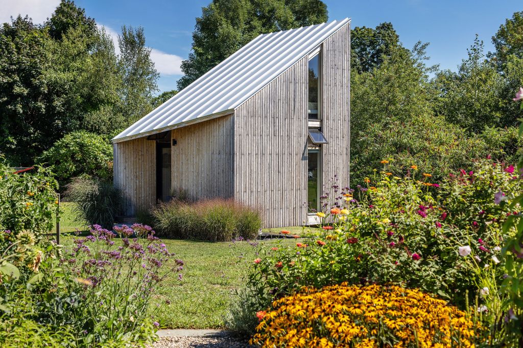 house with slanted roof surrounded by flowers and forrest