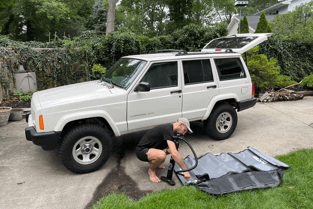 man setting up a flated air carrier and putting it on a jeep roof