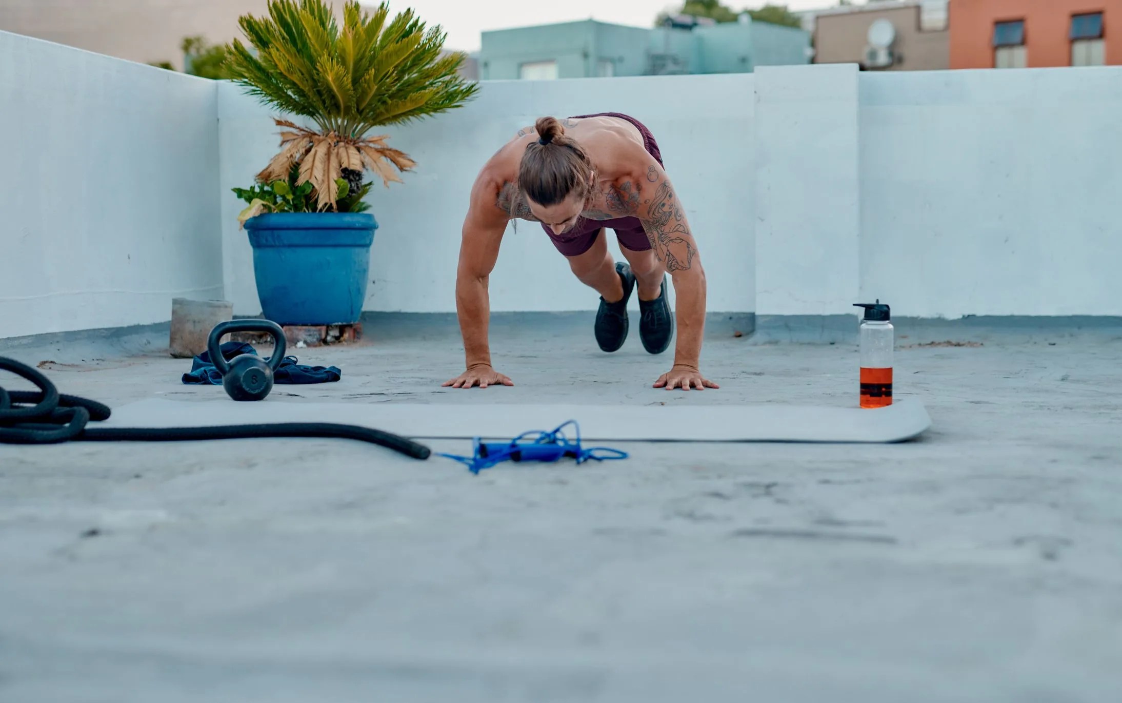 full length shot of a handsome young man doing burpees during a workout on the rooftop