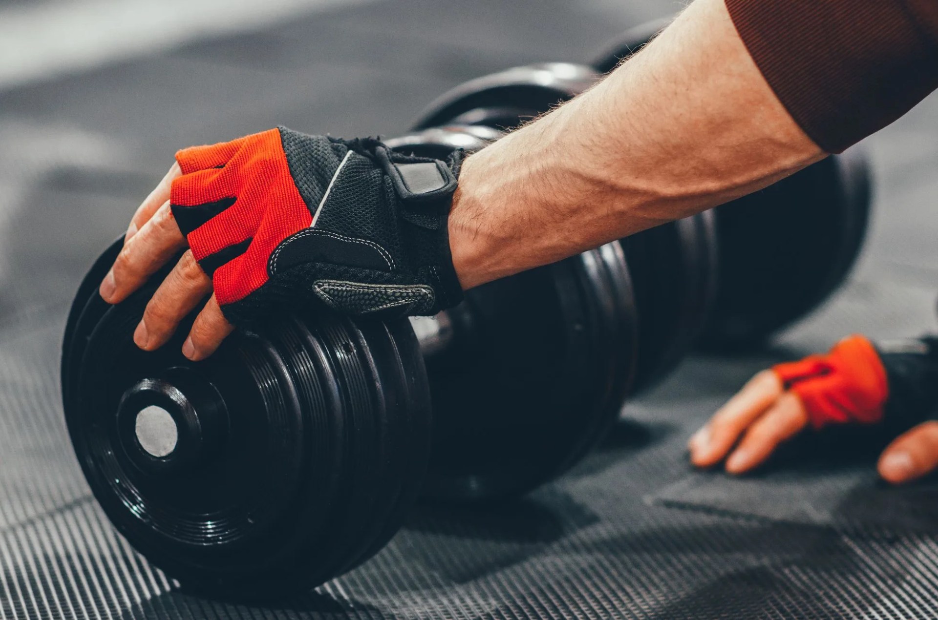gym workout cropped shot of male athlete in sport gloves choosing dumbbell for training at gym copy space