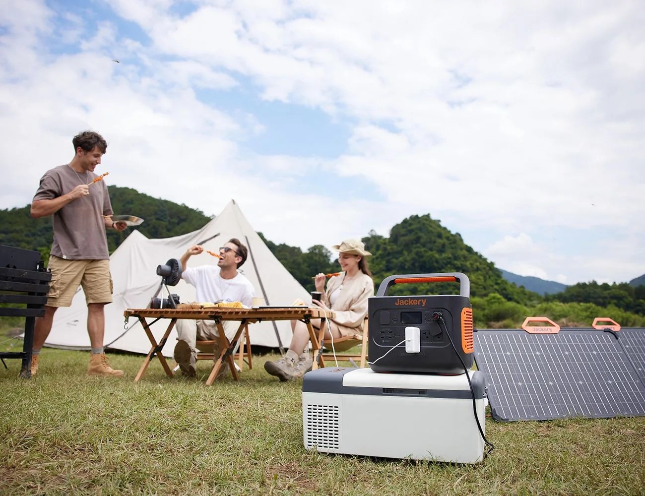 friends eat dinner around a table while a jackery solar generator 1000 pro charges their computer