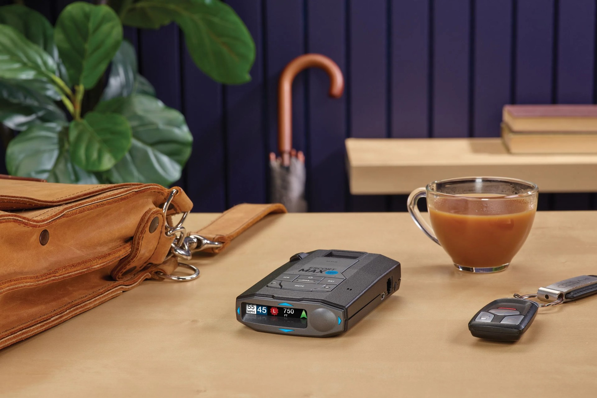 radar detector sitting on desk next to a briefcase, car keys, and cup of coffee
