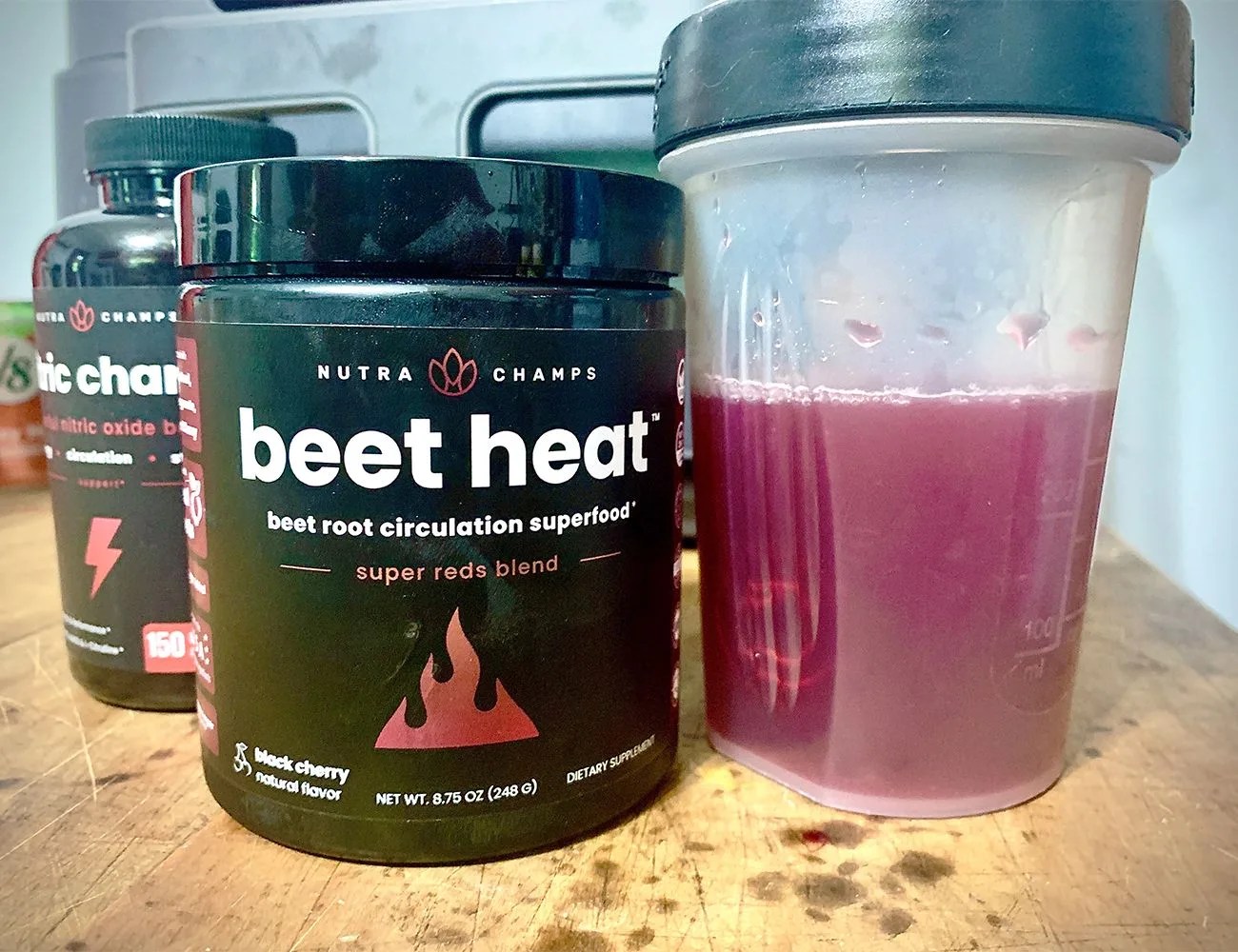beet heat powder jar next to a blender bottle