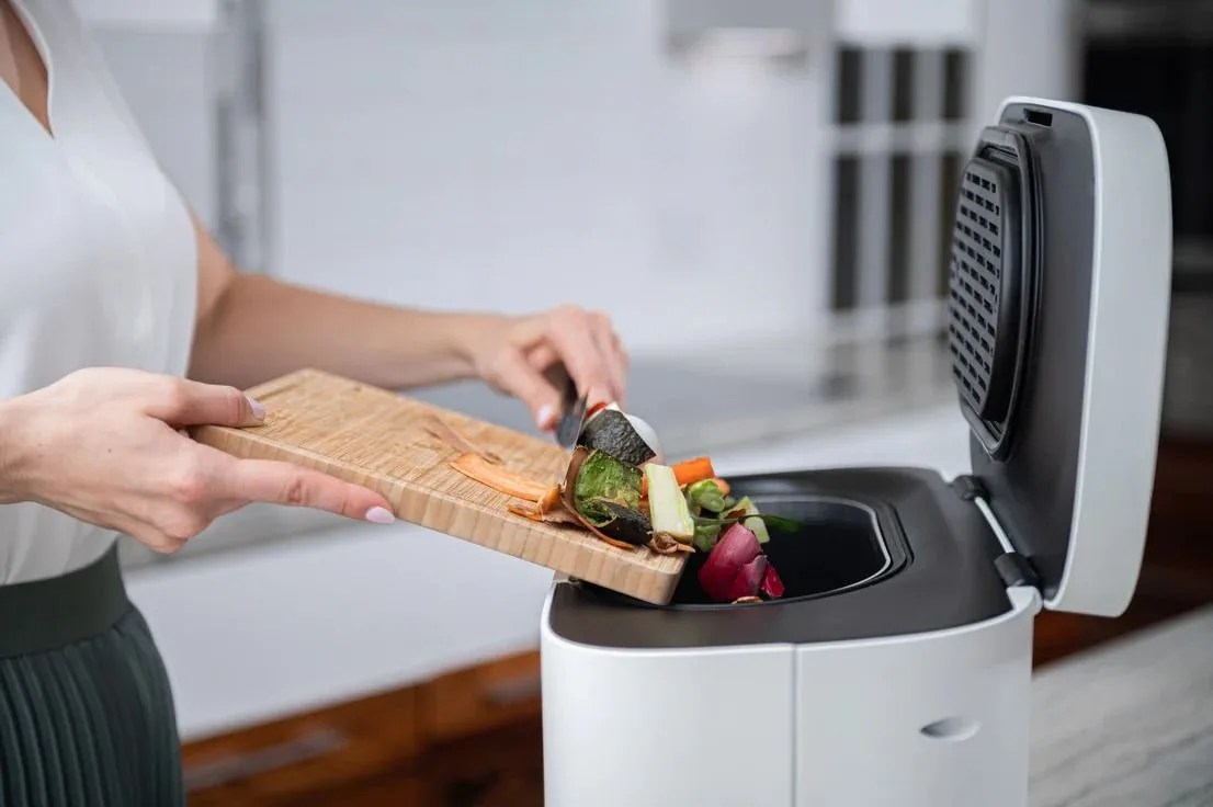 woman putting food scaps in a countertop composter