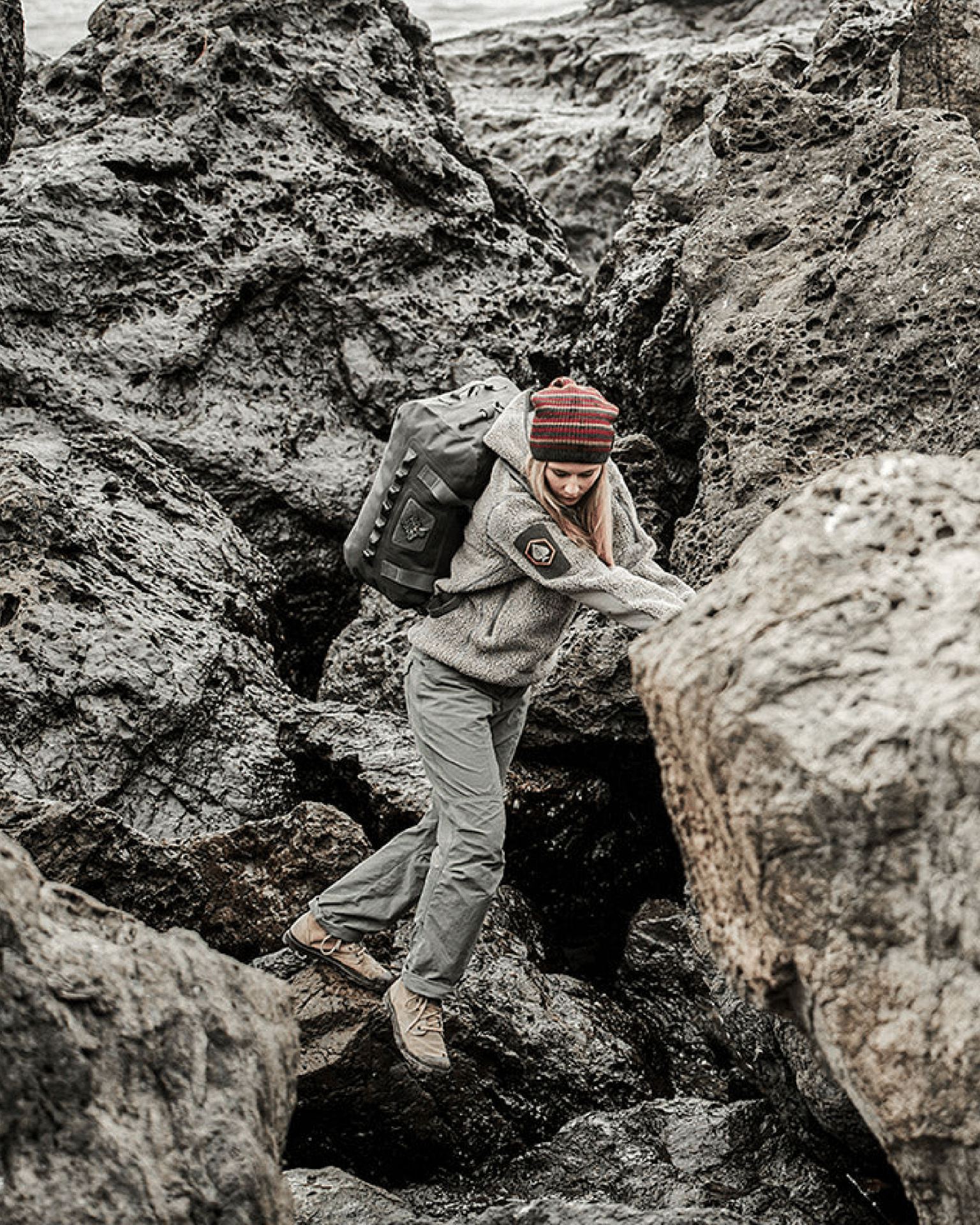a woman scaling rocks while carrying a  prometheus design werx all terrain duffel 60l