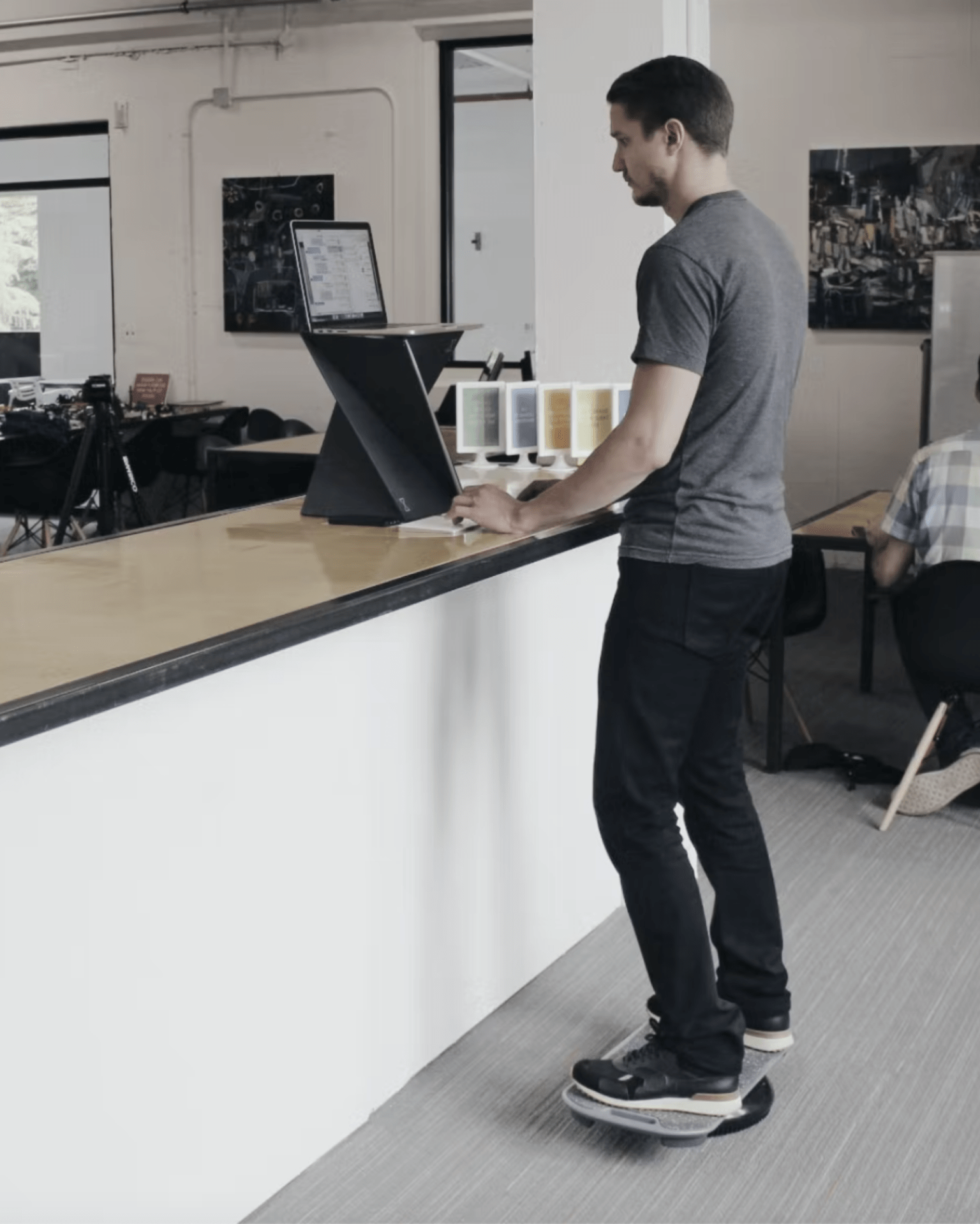 a man working at his laptop while standing on a 
revolution balance boards revbalance focus