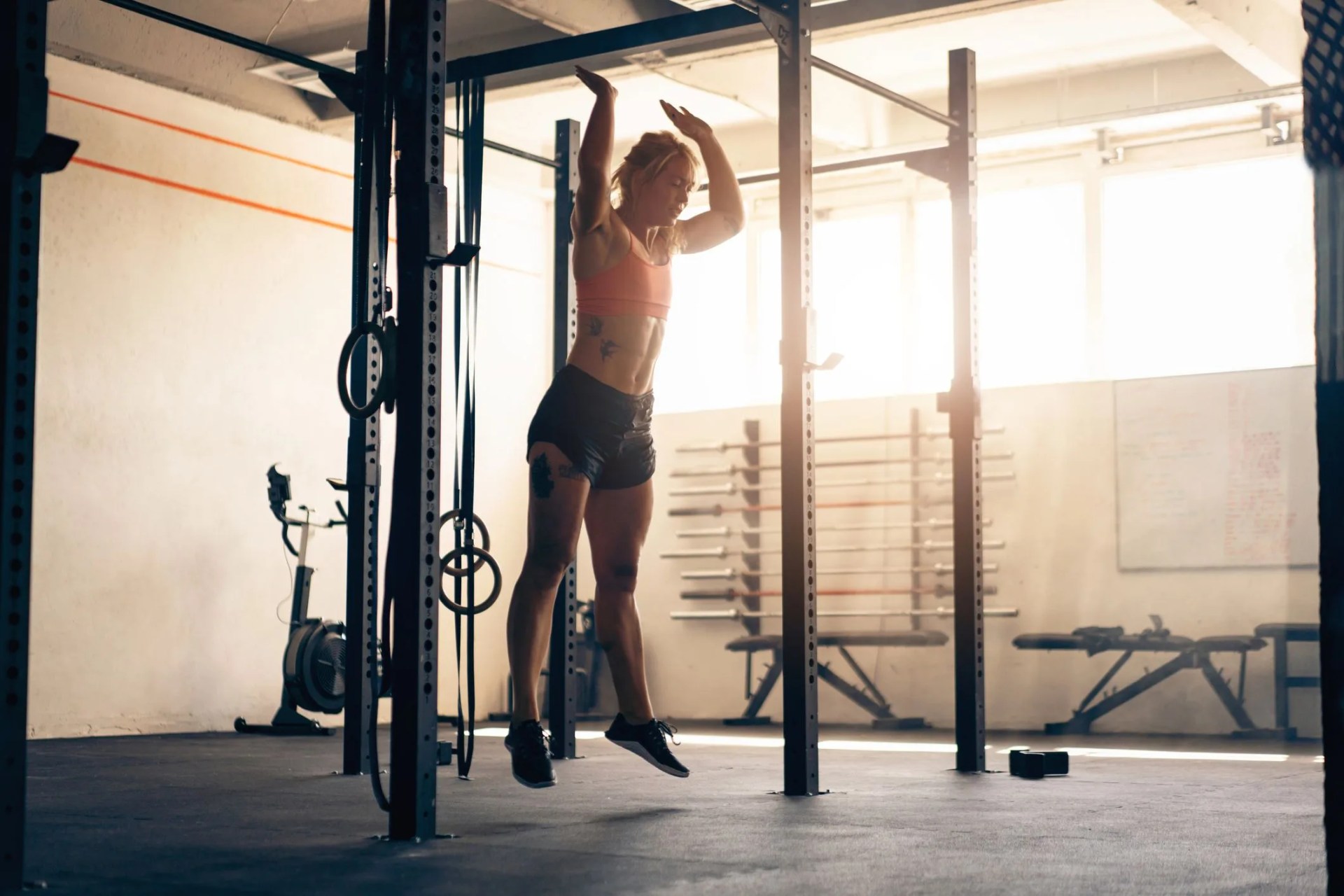 young caucasian woman, doing burpees at the modern gym