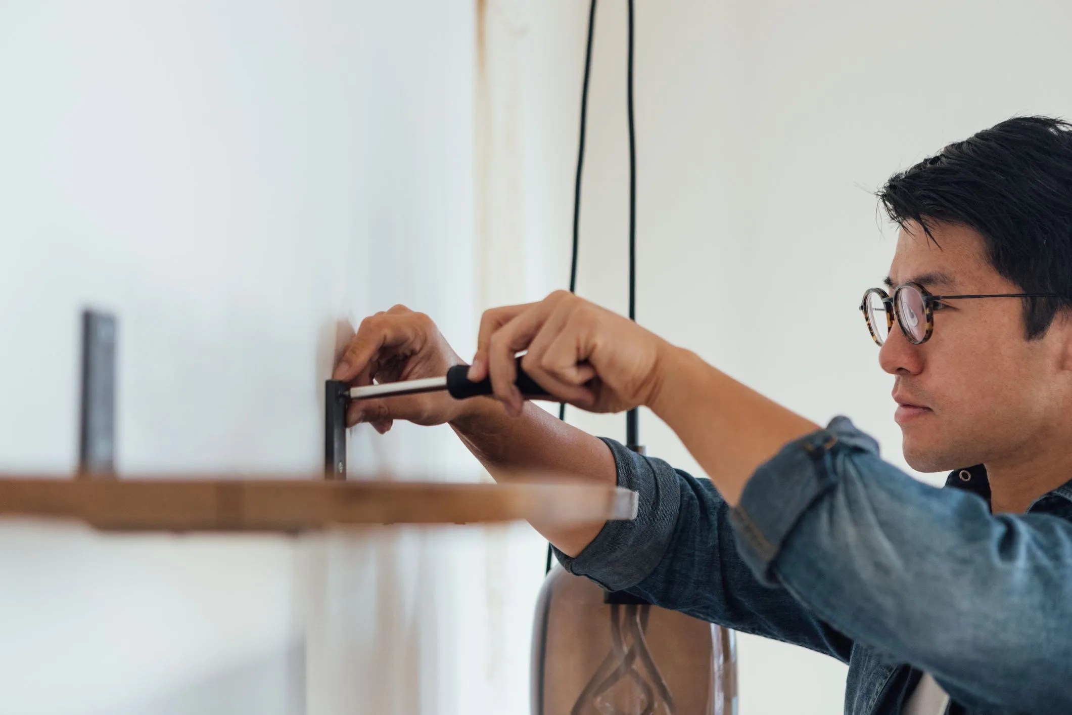 young man fixing a shelf with screwdriver at home