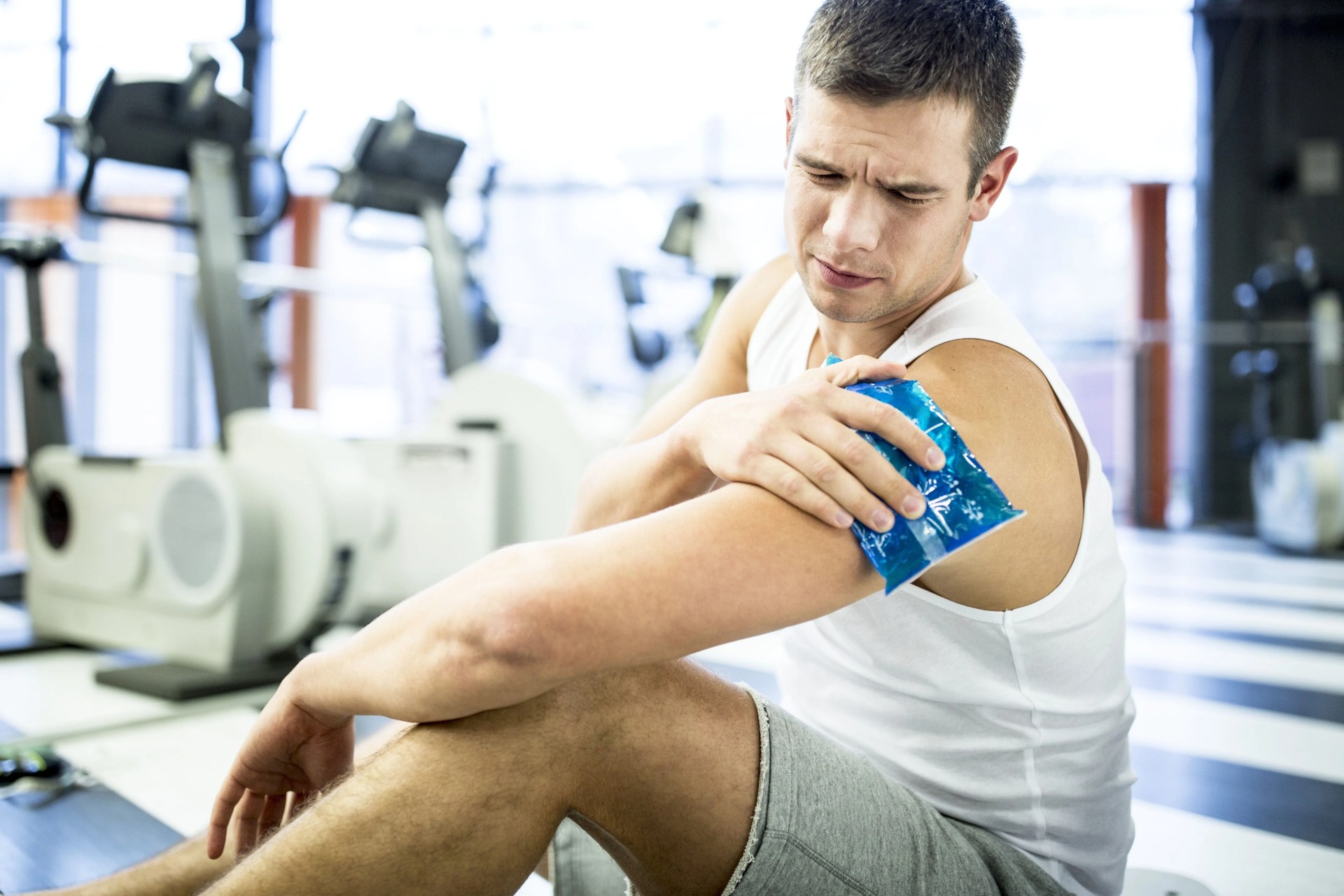 young man holding ice pack on shoulder